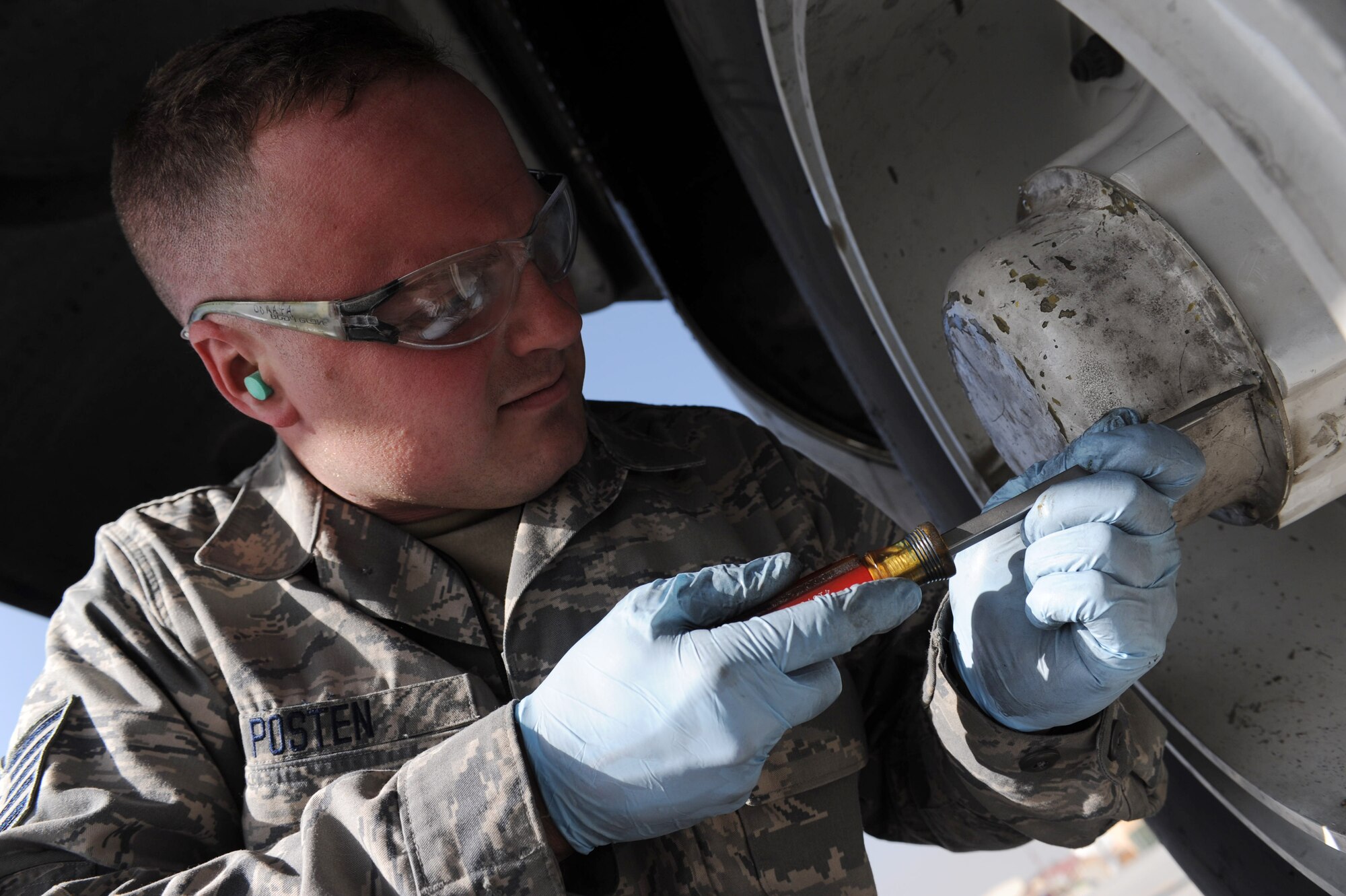 Tech. Sgt. John Posten, a C-130 crew chief assigned to the 123rd Airlift Wing, Kentucky Air National Guard, removes screws during a tire change  at Bagram Airfield, Afghanistan, November 29, 2010. Sergeant Posten is a native of Louisville, Ky. (U.S. Air Force photo/Staff Sgt. Christopher Boitz)