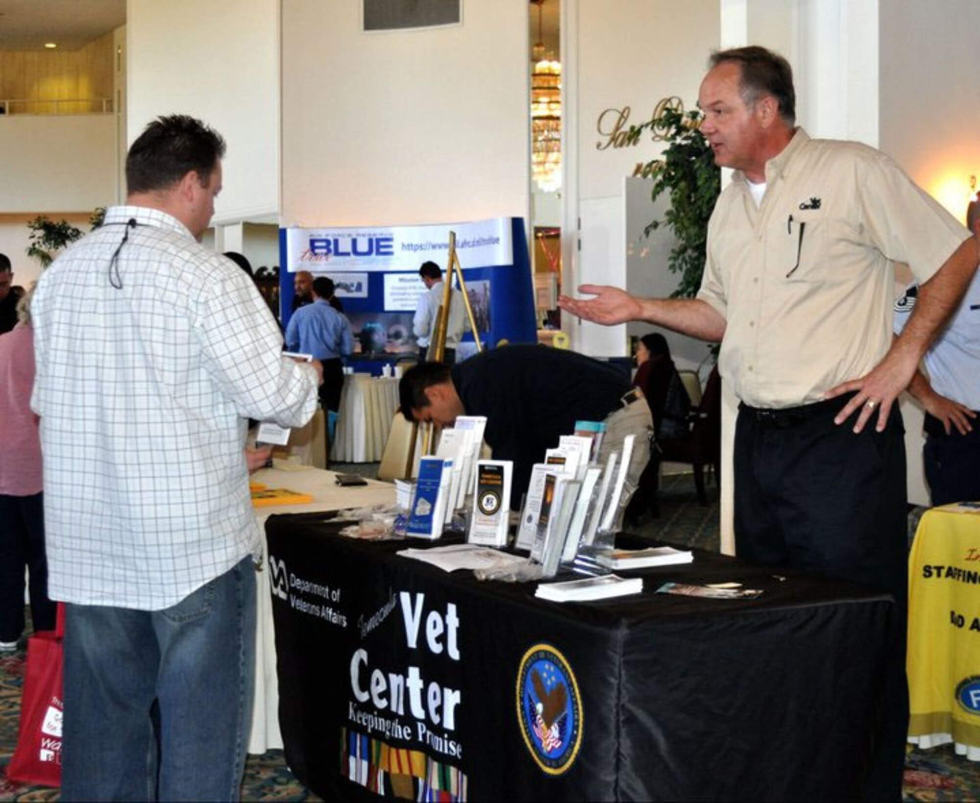 Wayne Grajczyk explains what Temecula's Vet Center has to offer as a service member makes his way around the room full of resourceful representatives present at this Yellow Ribbon event. March Air Reserve Base held a Yellow Ribbon event November 12-14 in San Diego with Airmen attending from March, Beale, McChord and Travis Air Bases.    (U.S. Air Force photo by Valerie M Palacios)