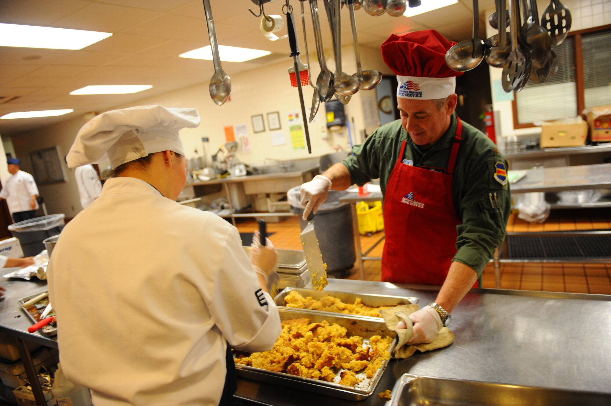 OFFUTT AIR FORCE BASE, Neb. - Maj. Doug Beidler, from the 38th Reconnaissance Squadron, dons his chef hat as he gets to work preparing stuffing with help from Senior Airman Lana Fowler at the Ronald L. King Dining facility for an annual Thanksgiving dinner Nov. 25.  Airmen, retirees and their families got a chance to have their Thanksgiving dinner professionally prepared by the Air Combat Command John L. Hennessy award winning Airmen while wing leadership served the food. U.S. Air Force photo by Josh Plueger (Released)
