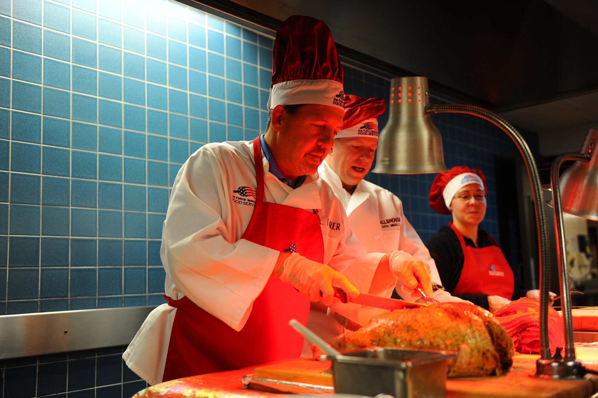 OFFUTT AIR FORCE BASE, Neb.- Thomas Fahrer, 55th Force Support Squadron deputy commander, and Col. Michael Allshouse, 55th Mission Support Group commander, carve up turkey and ham at the Ronald L. King Dining facility for Thanksgiving, Nov. 25.  Airmen, retirees and their families got a chance to have their Thanksgiving dinner professionally prepared by the Airmen of the dining facility while wing leadership served the food. U.S. Air Force photo by Josh Plueger (Released)
