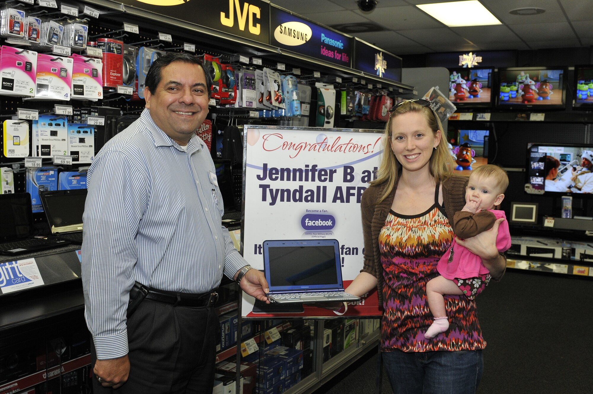 Alfredo Fuentes, Tyndall Base Exchange general manager, presents customer Jennifer Boyles with a Toshiba Mini 10.1 Netbook Nov. 29 at the Tyndall BX. Ms. Boyles is the spouse of a retired Air Force major. She won the prize through the Army & Air Force Exchange Service Salute Your Service Sweepstakes, a contest held every year Air Force-wide that includes seven prizes total. Customers enter the sweepstakes through the AAFES Facebook site. (U.S. Air Force photo by Lisa Norman)