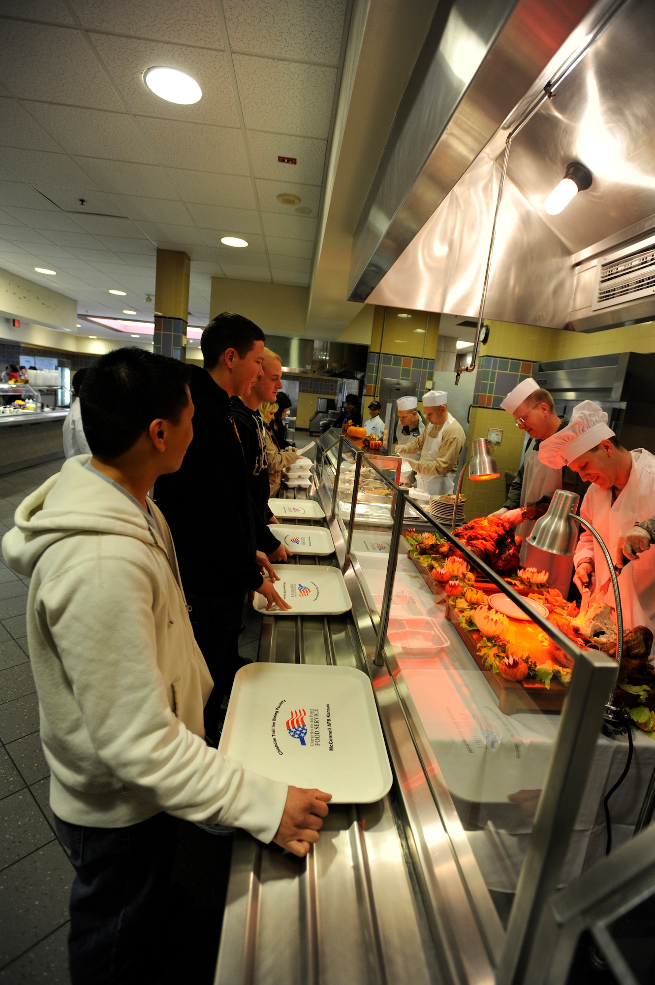 (Right to left)Team McConnell members wait in line as Col. Jamie Crowhurst, 22nd Air Refueling Wing commander, carves a turkey at the base dining facility, Nov. 25, 2010, McConnell Air Force Base, Kan. Colonel Crowhurst along with other McConnell leadership, spent part of Thanksgiving Day serving a home cooked meal. (U.S. Air Force Photo/Airman 1st Class Armando A. Schwier-Morales)