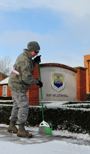 RAF MILDENHALL, England -- Master Sgt. Ani Stubbs, 100th Air Refueling Wing assistant to the director of staff, sweeps snow from the sidewalk in front of the 100th ARW headquarters building Nov. 29, 2010. The first snow of winter has now arrived at Mildenhall, and everyone is advised to take care, both when walking and driving in the snow. As temperatures drop below freezing, roads and sidewalks become a major hazard when covered in black ice. (U.S. Air Force photo/Karen Abeyasekere)