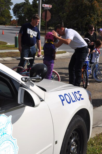 Airman 1st Class Steven Dickey, 325th Security Forces Squadron community police, assists a Team Tyndall dependent with learning how to properly secure her helmet Nov. 20 during the third-annual Bike Rodeo. (U.S. Air Force photo by Airman 1st Class Rachelle Elsea)