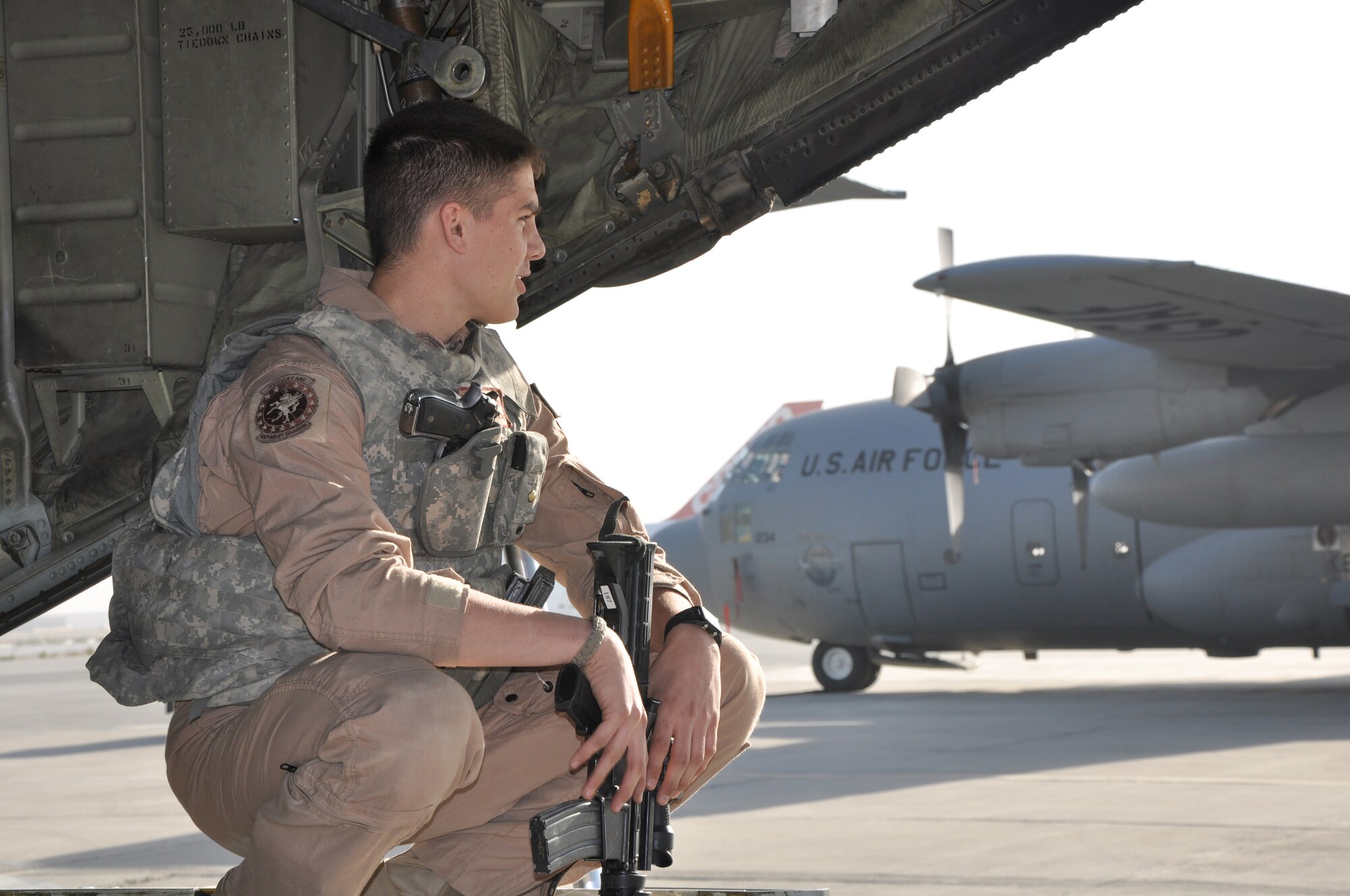 Senior Airman Jordan Gunterman, a 379th Air Expeditionary Wing fly away security team leader, crouches aboard a Kentucky Air National Guard C-130 at Bagram Airfield, Afghanistan.  (U.S. Air Force Photo/Capt. Erick Saks)