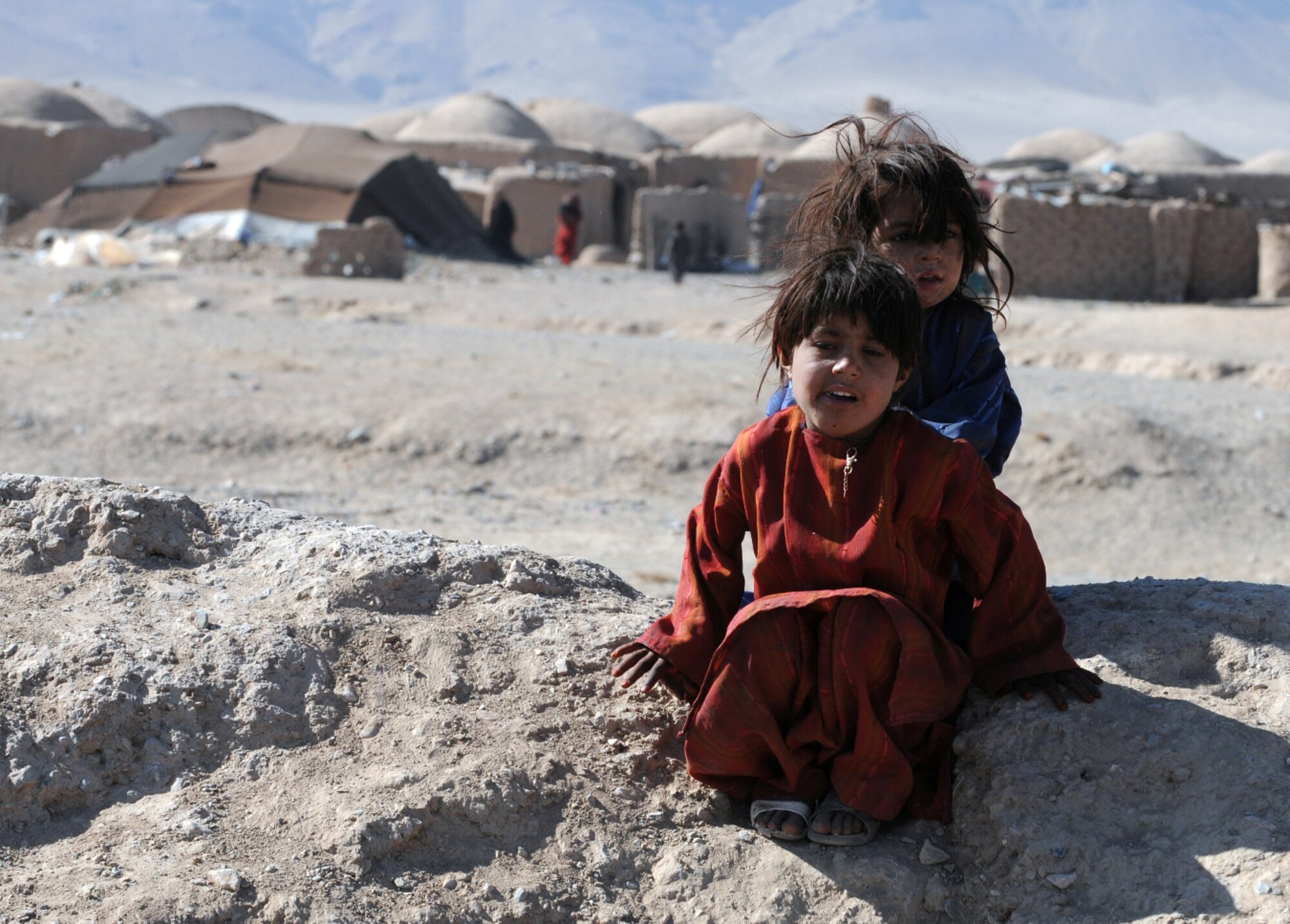 HERAT, Afghanistan -- Two Kuchi childern sit along the roadside after receiving shoes, candy and toys during a U.S. Forces-Afghanistan Detachment West-sponsored humanitarian mission to their village in Herat province Nov. 18, 2010. Historically, most Afghans looked down on the Kuchi because they were traveling people and were not rooted anywhere, but day by day the perception of the Kuchi is increasing as Afghans become more open minded and Afghans begin to look at the Kuchi as equal brothers and sisters. (U.S. Air Force photo/Tech. Sgt. Kevin Wallace)