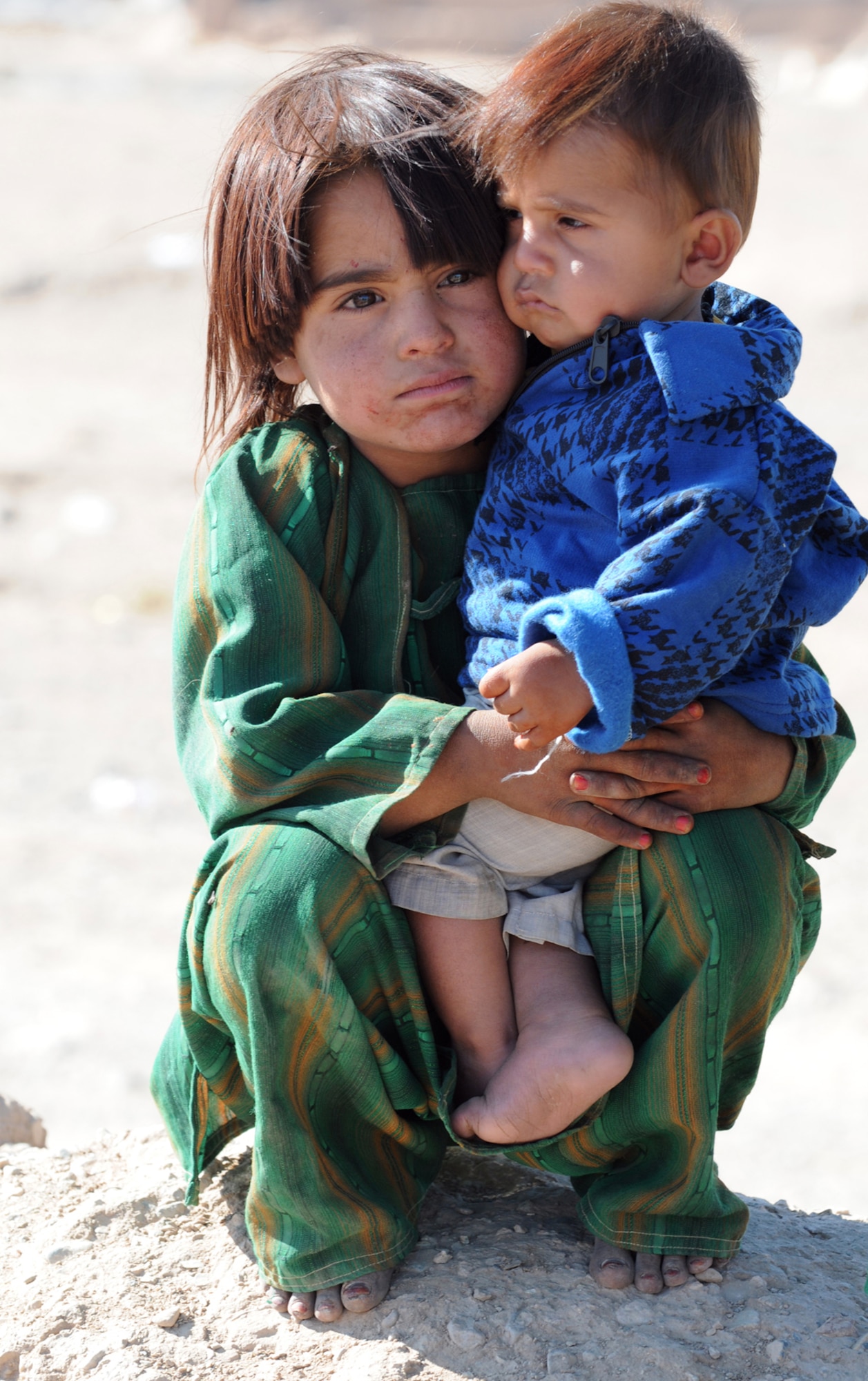 HERAT, Afghanistan -- A Kuchi girl holds her little brother and waits patiently for their turn to receive shoes, candy and toys during a U.S. Forces-Afghanistan Detachment West-sponsored humanitarian mission to their village in Herat province Nov. 18, 2010. Historically, most Afghans looked down on the Kuchi because they were traveling people and were not rooted anywhere, but day by day the perception of the Kuchi is increasing as Afghans become more open minded and Afghans begin to look at the Kuchi as equal brothers and sisters. (U.S. Air Force photo/Tech. Sgt. Kevin Wallace)
