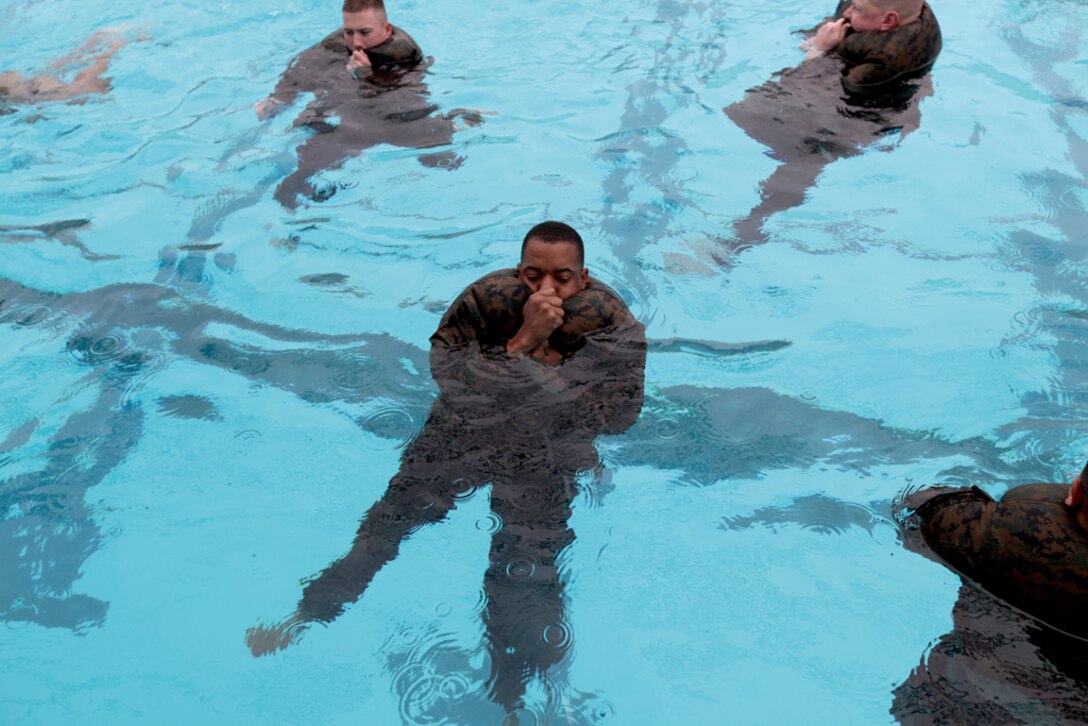 Lance Cpl. Sean Cortez, a motor transport operator with Headquarters Company, Combat Logistics Regiment 37, 3rd Marine Logistics Group, III Marine Expeditionary Force, performs a blouse inflation technique in the 25-meter pool on Camp Hansen during his swim qualification Nov. 30. Cortez was one of the last Marines on Okinawa to conduct swim qualification training under the old training regulations.