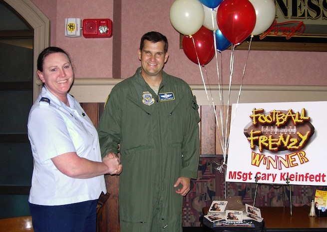 Master Sgt. Gary Kleinfeldt is joined by Maj. Tara White at the Charleston Club on Joint Base Charleston, S.C., Nov. 15, 2010, after she surprised him with the news he had won the drawing for the Air Force Services Agency's Football Frenzy promotion. He and a friend will receive a trip package for a six-day, five-night trip to Dallas, Texas, to watch the Dallas Cowboys play the Philadelphia Eagles, Dec. 12. The trip will include air fare, hotel accommodations, use of a rental car, a welcome breakfast Dec. 10, a tailgate lunch prior to the game in addition to two free tickets to the game. A farewell dinner will be held Dec. 13 before their trip home Dec. 14. The drawings for prizes will continue through Feb. 18 to select 10 Club members across the Air Force to receive $500 gift cards. The drawing for the ultimate prize package takes place Jan. 5. Four Club members will be selected to attend the Super Bowl in Dallas Feb. 6. Major White is the 628th Force Support Squadron commander and Sergeant Kleinfeldt is the operations superintendent for the 14th Airlift Squadron. (Courtesy photo)
