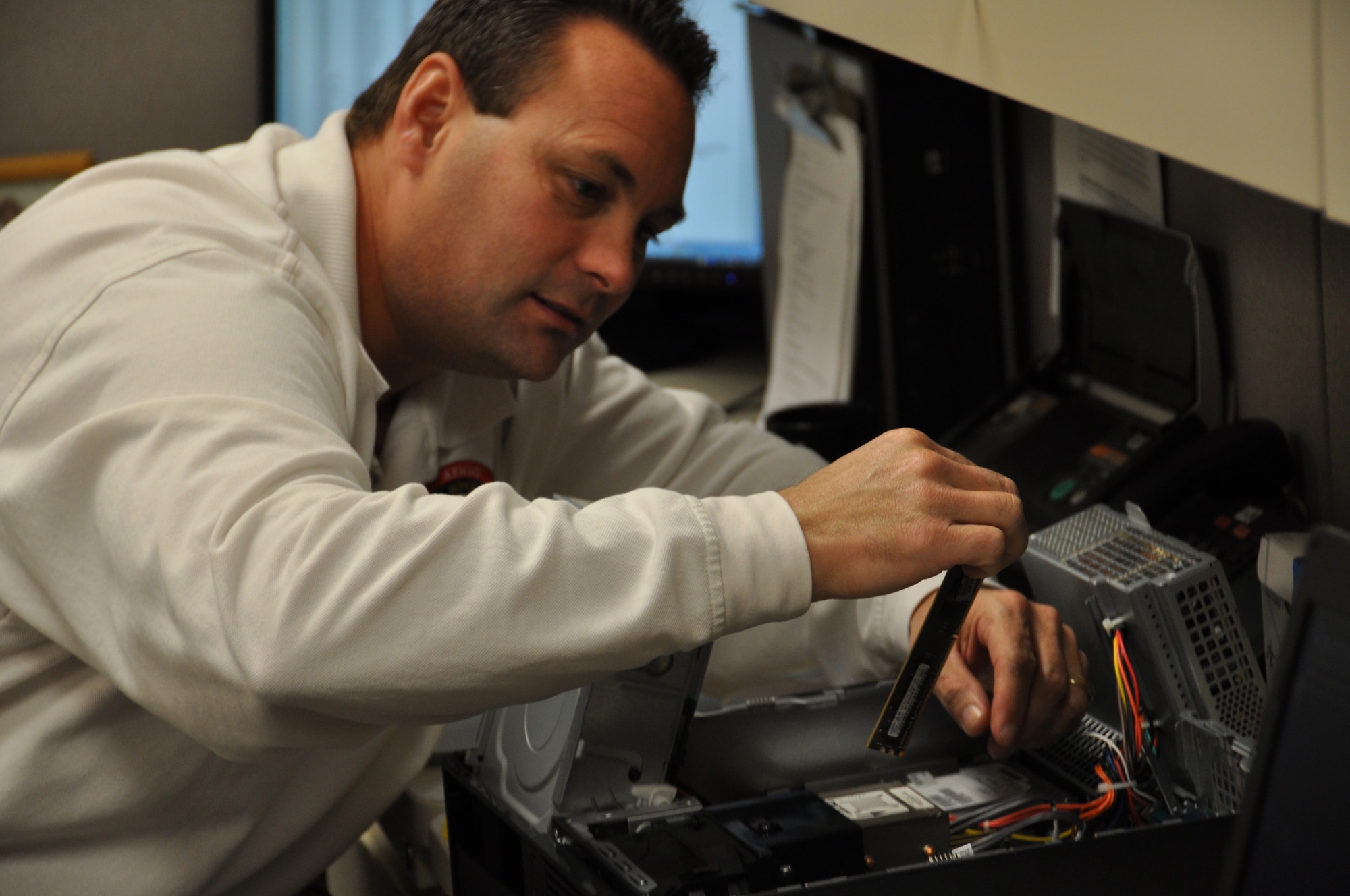 Stephen Cortes, assistant technical operations officer, replaces a motherboard in a computer at Air Force Mortuary Affairs Operations Nov. 30, 2010. Mr. Cortes is one member of the Information Technology team which serves as one part of the backbone of mortuary operations. (U.S. Air Force photo/Christin Michaud)