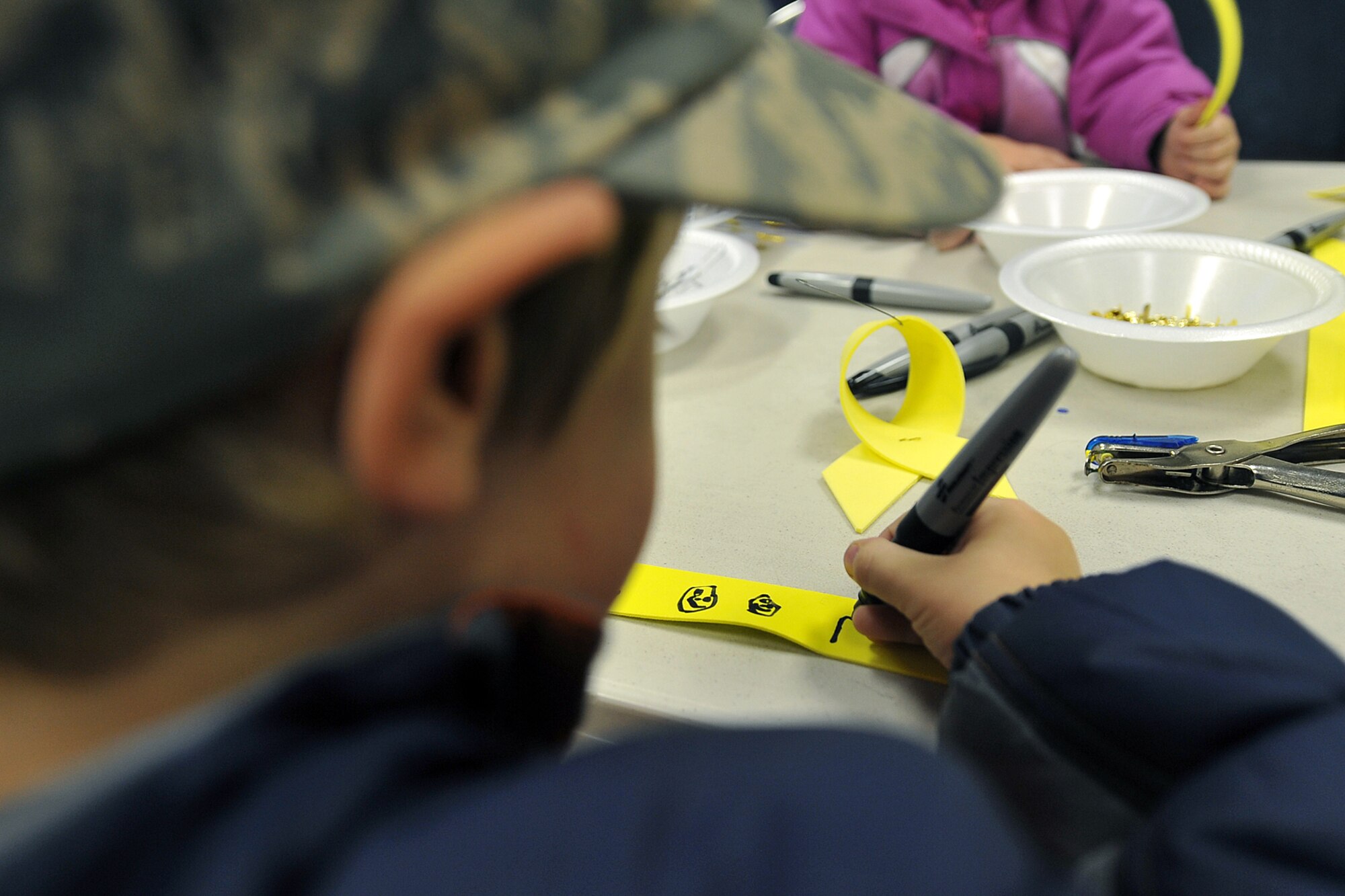 OFFUTT AIR FORCE BASE, Neb. - Elliott Cook decorates a ribbon Nov. 29 for his father, Staff Sgt. Jeffrey Cook assigned to the 55th Aircraft Maintenance Squadron, before a special dedication ceremony at Offutt's new Hero Park outside the SAC Memorial Chapel. Hero Park features a hero tree where Team Offutt members can hang ornaments, reflect on and pray for their deployed loved ones. U.S. Air Force photo by Charles Haymond (Released)