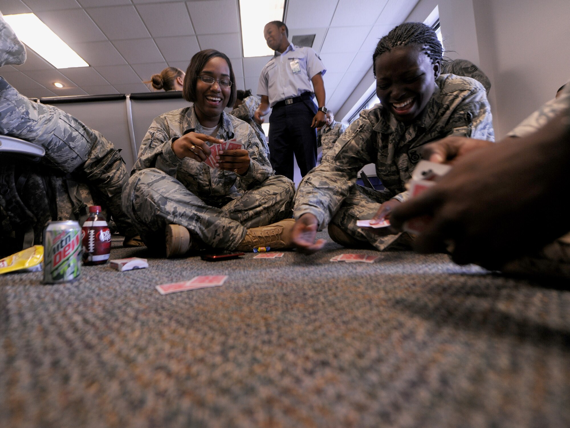 MOODY AIR FORCE BASE, Ga.-- Airmen 1st Class Alisa Baker and Daphane Stevens, 824th Base Defense Squadron fire team members, play a card game while waiting to be loaded onto a Boeing 757. Although the exact length varies, many squadrons deploy for approximately six months. (U.S. Air Force photo/Airman 1st Class Benjamin Wiseman)(RELEASED)