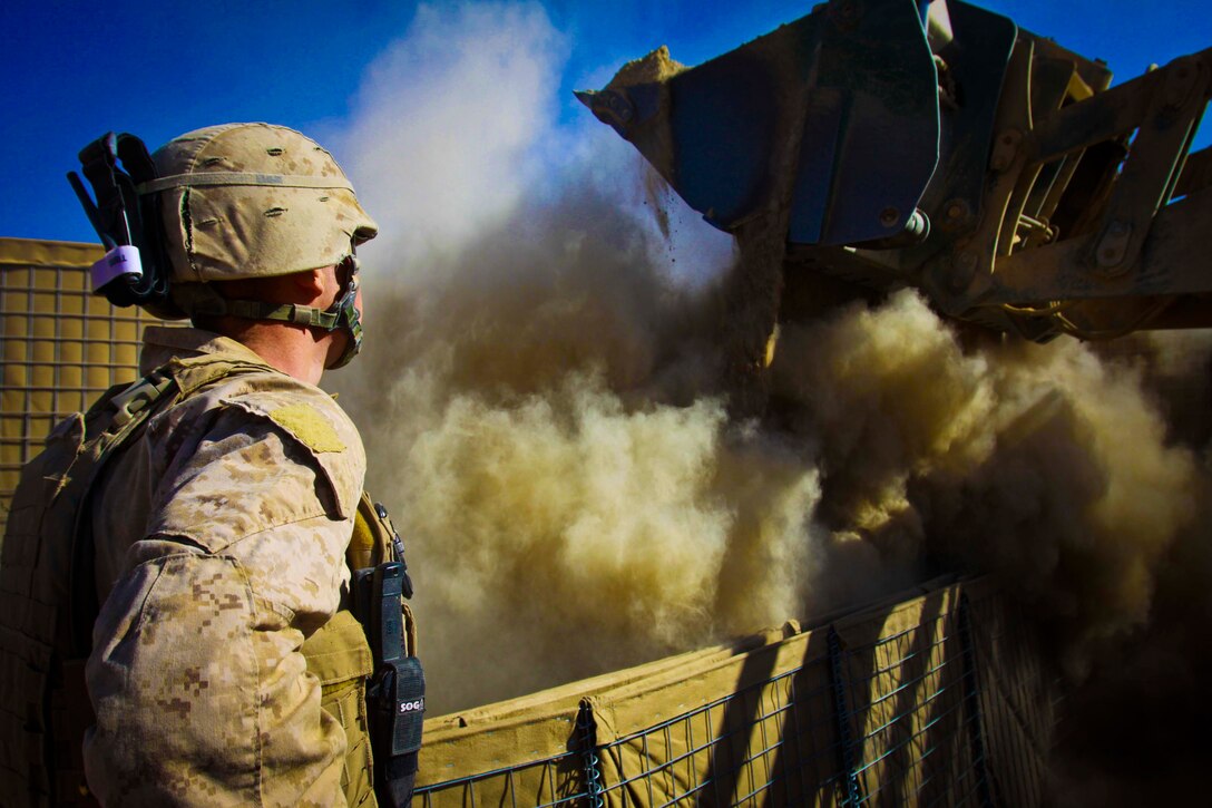 Lance Cpl. Gabe T. Green, 19, combat engineer,  Engineer Company, Combat Logistics Battalion 3, 1st Marine Logistics Group (Forward),  watches as dirt fills a barrier on Patrol Base Amir, Afghanistan, Nov. 30. Marines with CLB-3's Engineer Co. are currently expanding the patrol base.