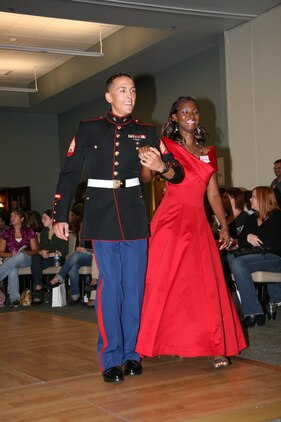 Sgt. Nicholas Voghel escorts TK Shuler around the floor to present the gown she is modeling during the fashion show portion of Operation Ball Gown at Miller’s Landing Friday. More than 300 ball gowns were donated to Marine Corps Community Services for the event. Nearly 200 gowns that were donated by the Whistle Stop Thrift Shop are still available to be purchased from the Whistle Stop.