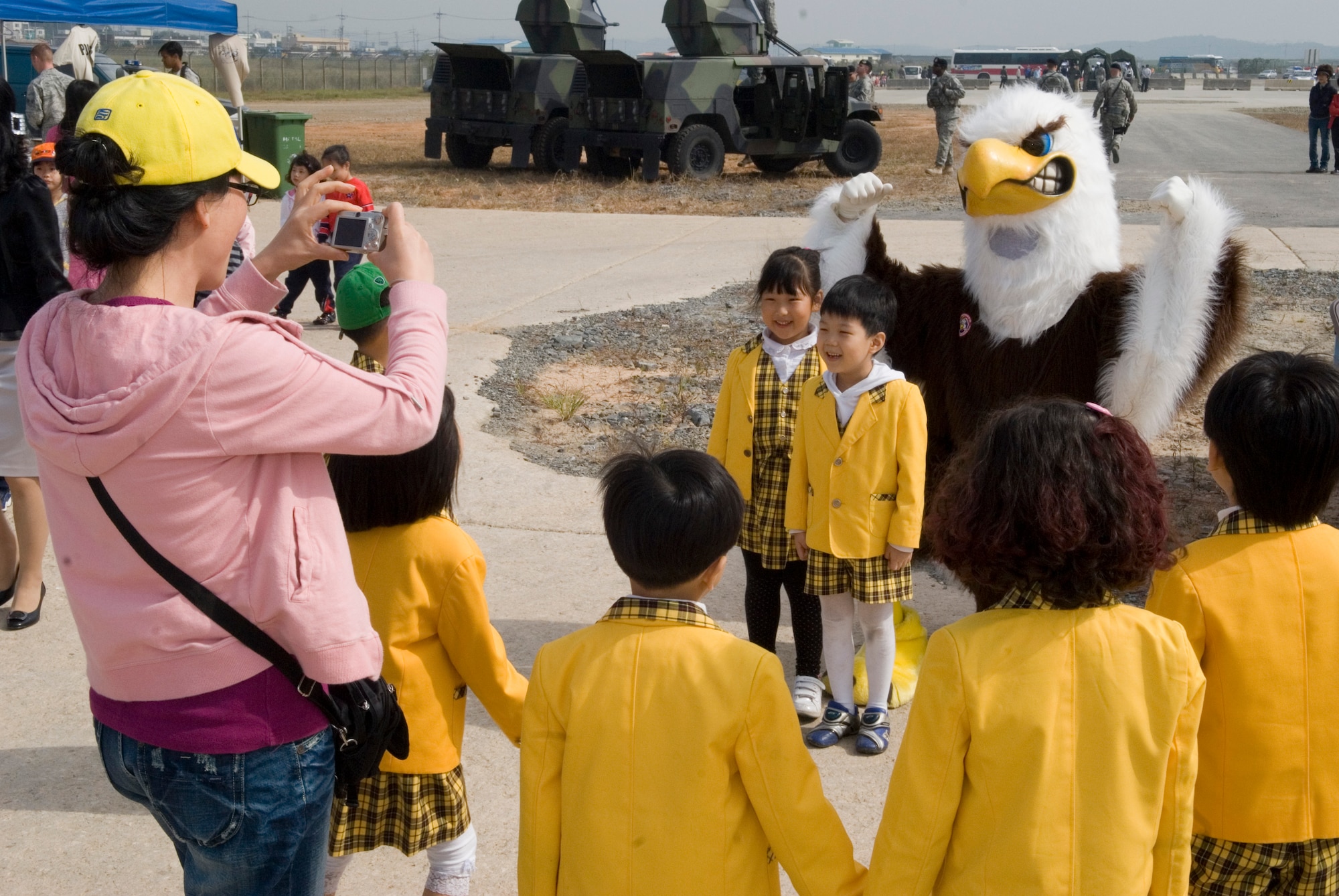KUNSAN AIR BASE, Republic of Korea -- Gunsan City school children take photos with Senior Airman Zach Vaughn, Armed Forces Network Eagle, during the Kunsan Air Base Open House and Gunsan Appreciation Day here Oct. 1, 2010. The base opened its doors to the local community and held events including an F-16 Fighting Falcon fly-by, Korean dance performances, static displays, organizational booths, military working dog demonstrations, aircraft munitions-loading competitions, music and more. (U.S. Air Force photo/Senior Airman Ciara Wymbs)