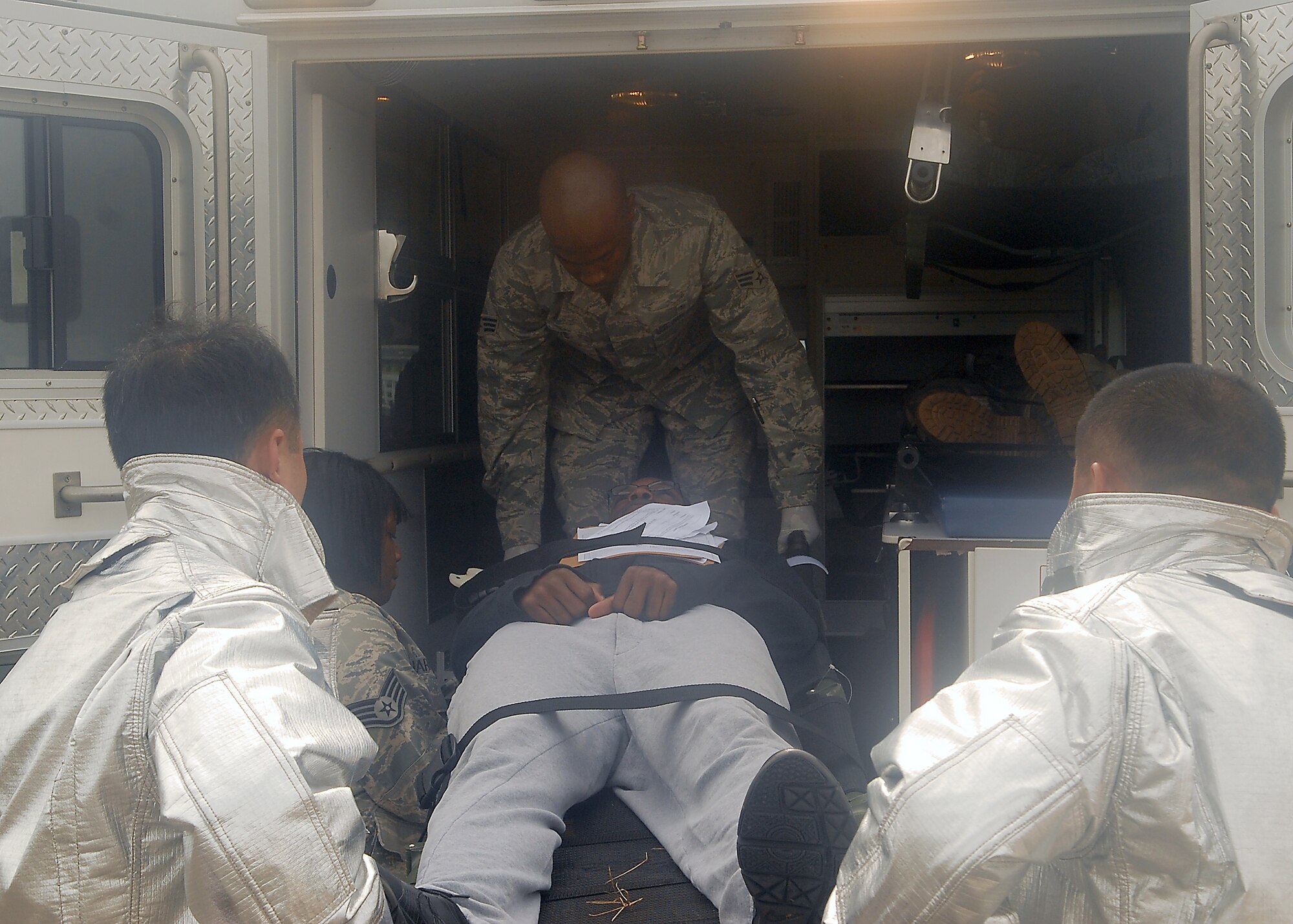 KUNSAN AIR BASE, Republic of Korea -- 8th Medical Group medics and 8th Civil Engineer Squadron firefighters work together to get victims of a simulated plane crash loaded into an ambulance during exercise Beverly Hotel 10-6 here Sept. 27, 2010. During the exercise Airmen worked together to get all the victims to safety, extinguish the burning aircraft, and practiced self-aid and buddy care. (U.S. Air Force photo/Senior Airman Ciara Wymbs) 