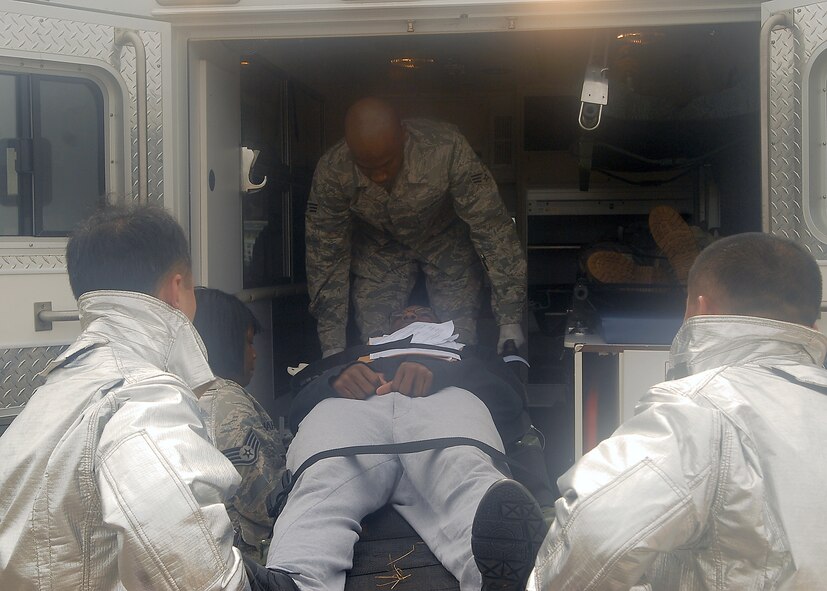 KUNSAN AIR BASE, Republic of Korea -- 8th Medical Group medics and 8th Civil Engineer Squadron firefighters work together to get victims of a simulated plane crash loaded into an ambulance during exercise Beverly Hotel 10-6 here Sept. 27, 2010. During the exercise Airmen worked together to get all the victims to safety, extinguish the burning aircraft, and practiced self-aid and buddy care. (U.S. Air Force photo/Senior Airman Ciara Wymbs) 