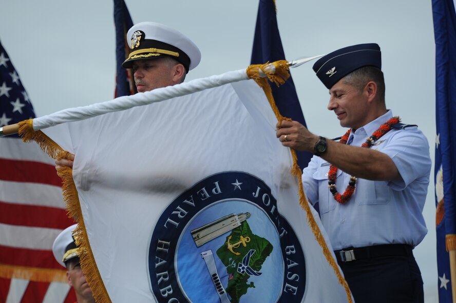 Capt. Richard Kitchens, Joint Base Pearl Harbor-Hickam commander, and Col. Charles Baumgardner, JBPHH deputy commander, unveil the JBPHH flag at the Full Operational Capability Commemoration Ceremony Oct. 1 at the Missing Man Formation Memorial at Aloha Aina Park. The FOC ceremony marks the joining of two historic military installations, Naval Station Pearl Harbor and Hickam Air Force Base. (U.S. Air Force photo by Staff Sgt. Nathan Allen)