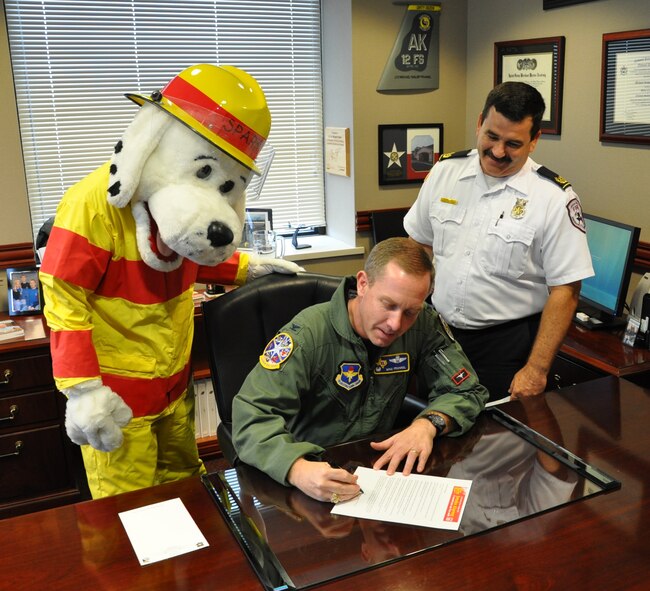 LAUGHLIN AIR FORCE BASE, Texas – Col. Michael Frankel, 47th Flying Training Wing commander, signs the declaration to recognize Oct. 3 through 9 as Fire Prevention Week at Laughlin as David Isbell, of Laughlin's Fire Department, and 'Sparky' look on. The Fire Department here will host several events including a search and rescue challenge. (U.S. Air Force photo by Airman 1st Class Blake Mize) 
