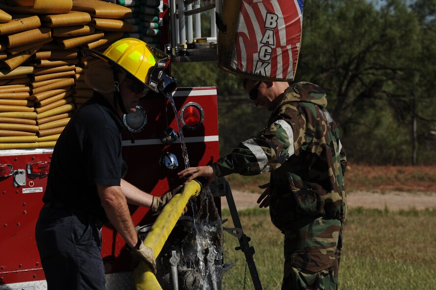 DYESS AIR FORCE BASE, Texas—Brian Slaughter (left) and Staff Sgt. Gerald Allen, 7th Civil Engineer Squadron firefighters, connect a water hose to a fire truck during a training exercise here, Sept. 30. The squadron has more than 55 firefighters and operates more than 15 fire trucks. Some days the station gets up to ten calls and the firefighters are required to be on scene within five minutes of the call. They conduct routine safety checks on buildings as well as practice procedures in case of a fire.  (U.S Air Force photo/ Airman 1st Class Shannon Hall)