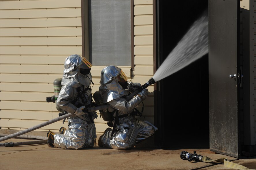 DYESS AIR FORCE BASE, Texas—Staff Sgt. Gerald Allen (left) and Airman Tyler Ellie, 7th Civil Engineer Squadron firefighters, put out a fire during a training exercise here, Sept. 30.  The squadron has more than 55 firefighters and operates more than 15 fire trucks. Some days the station gets up to ten calls and the firefighters are required to be on scene within five minutes of the call. They conduct routine safety checks on buildings as well as practice procedures in case of a fire.  (U.S Air Force photo/ Airman 1st Class Shannon Hall)
