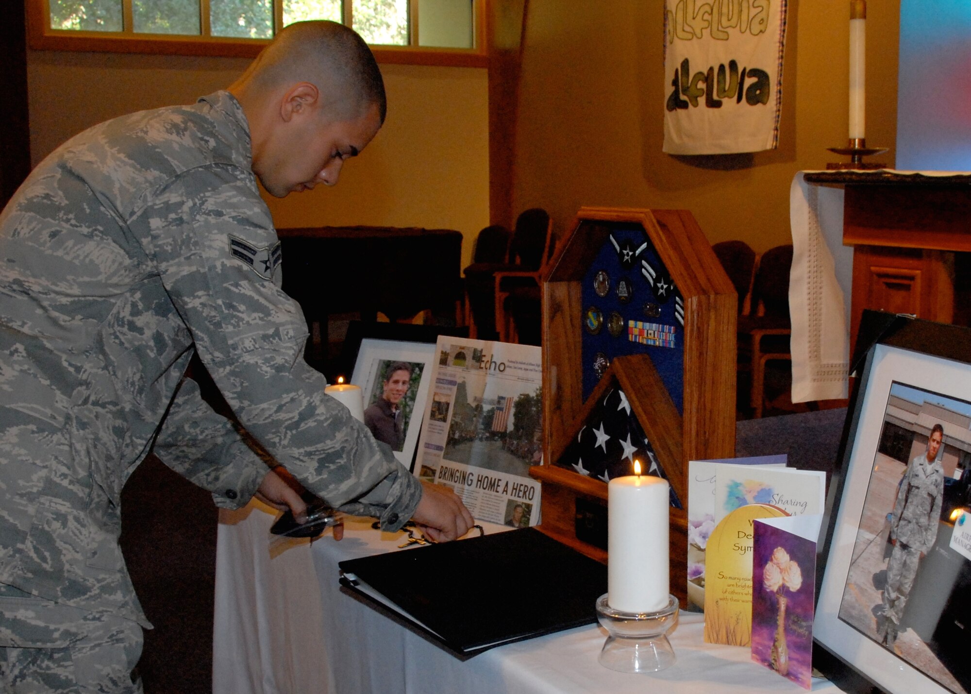 Airman Anthony Puma arranges memories of his fallen comrade during his wing's Memorial Ceremony for Senior Airman James Hansen Oct. 1 at the East Gate Chapel. The 46th Test Wing, Eglin senior leaders and the base community gathered  together to commemorate the life of the airfield management operations Airman who died Sept. 15 from injuries received during a controlled detonation at Joint Base Balad, Iraq.  (U.S. Air Force photo/Sachel Seabrook)
