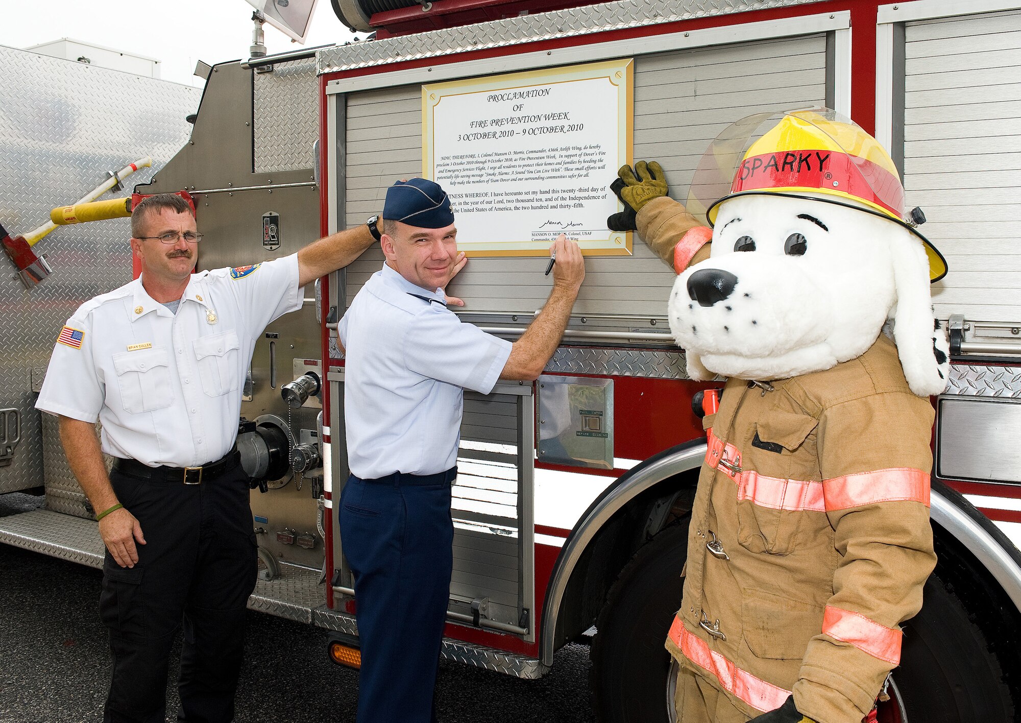 Col. Manson Morris, 436th Airlift Wing commander, signs the Fire Prevention Week Proclamation, as Brian Cullen, 436th Civil Engineers Squadron assistant fire chief, and Sparky look on at Dover Air Force Base, Del., Sept. 27, 2010. Fire Prevention Week is Oct. 3 - 9, 2010, and will focus on fire safety and prevention. (U.S. Air Force photo by Jason Minto/Released)