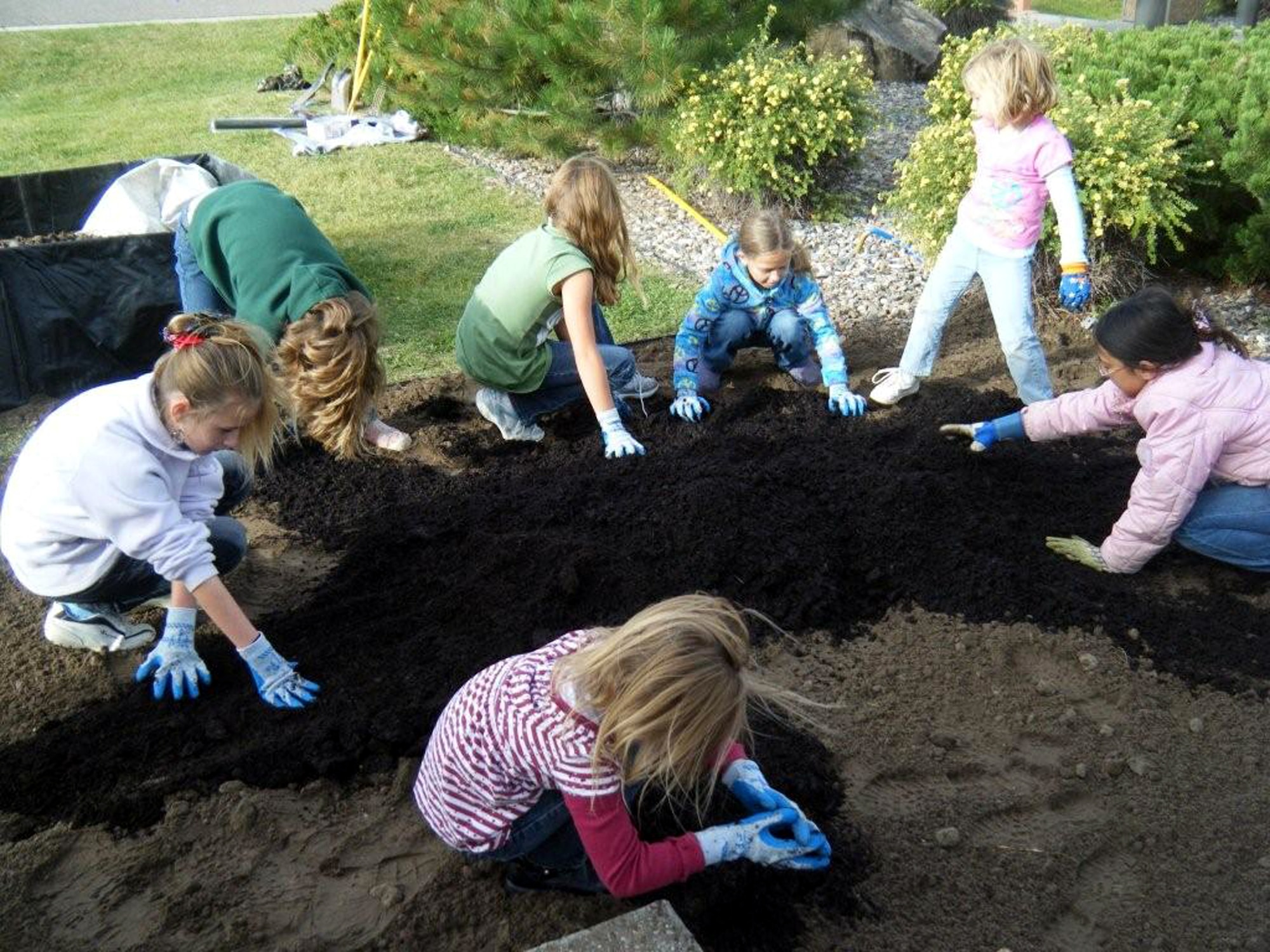 Members of Girl Scout Junior Troop 3135 spread fertilizer around the bedding of their garden for phase one of their National Public Lands Day project at Medal of Honor Park.  (U.S. Air Force photo/Airman 1st Class Kristina Overton)
