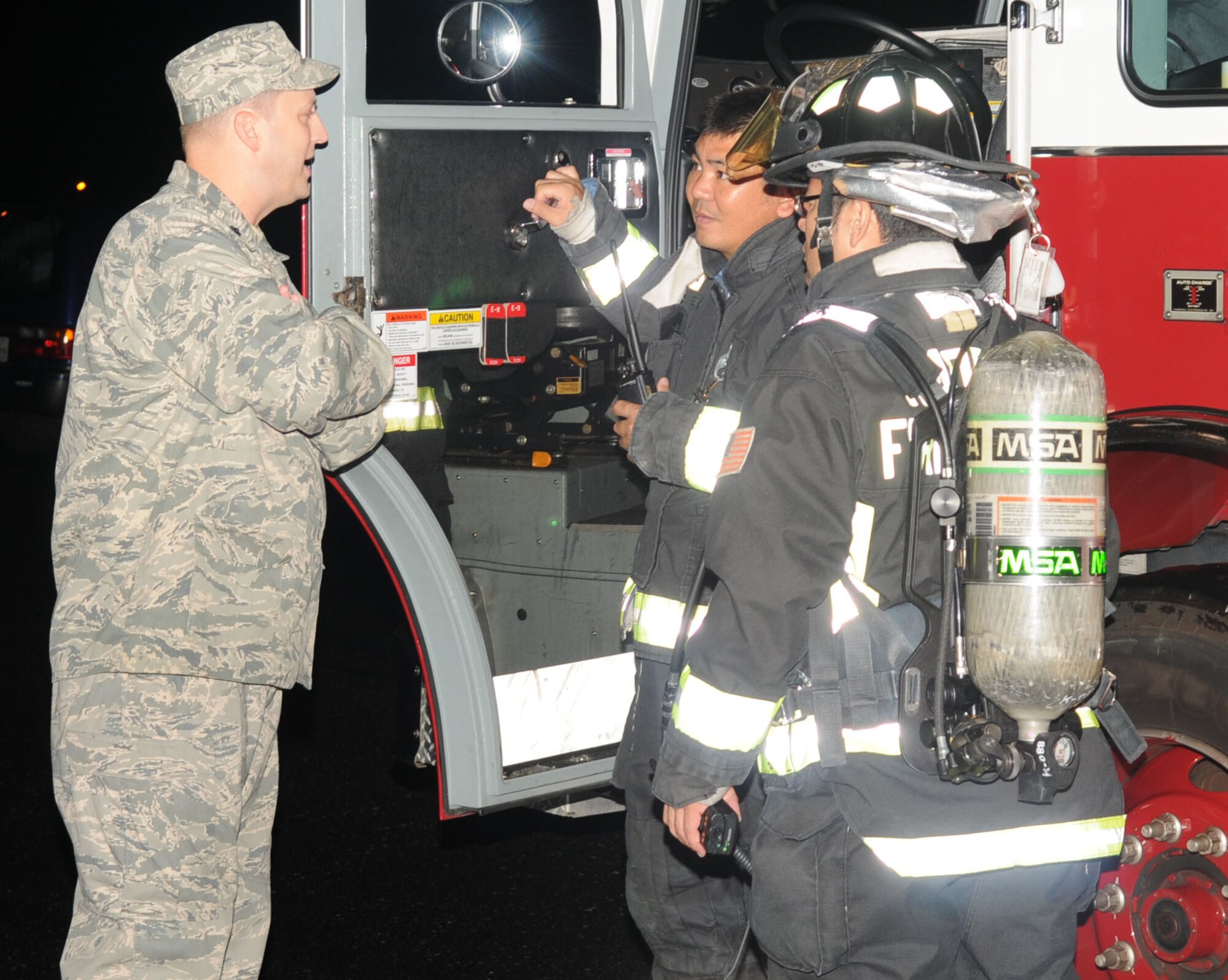Lt. Col. Phillip Hendrix, 18th Contracting Squadron commander, asks Kadena firefighters about getting back into his facility as soon as possible after a false fire alarm evacuated the entire building Sept. 30. The 18th Contracting Squadron workers got back to work with 15 minutes left to help customers make their final purchases before next fiscal year. (U.S. Air Force photo by Tech. Sgt. Mike Tateishi)