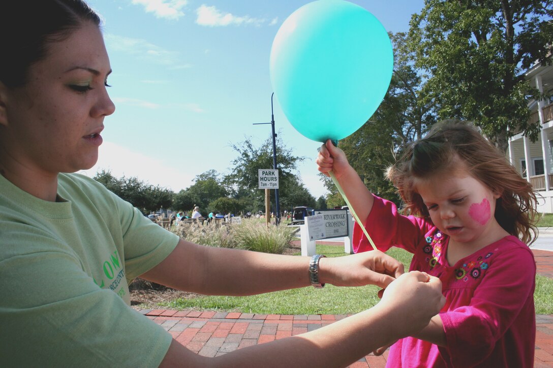 Petty Officer 2nd Class Casey O’Neill ties a balloon to her three-year-old daughter, Mykayla, during a charity event in Jacksonville, N.C., Oct. 2, 2010.  The event included the organization’s 2nd annual charity walk, face painting, refreshments, and prizes for different teams and groups involved.