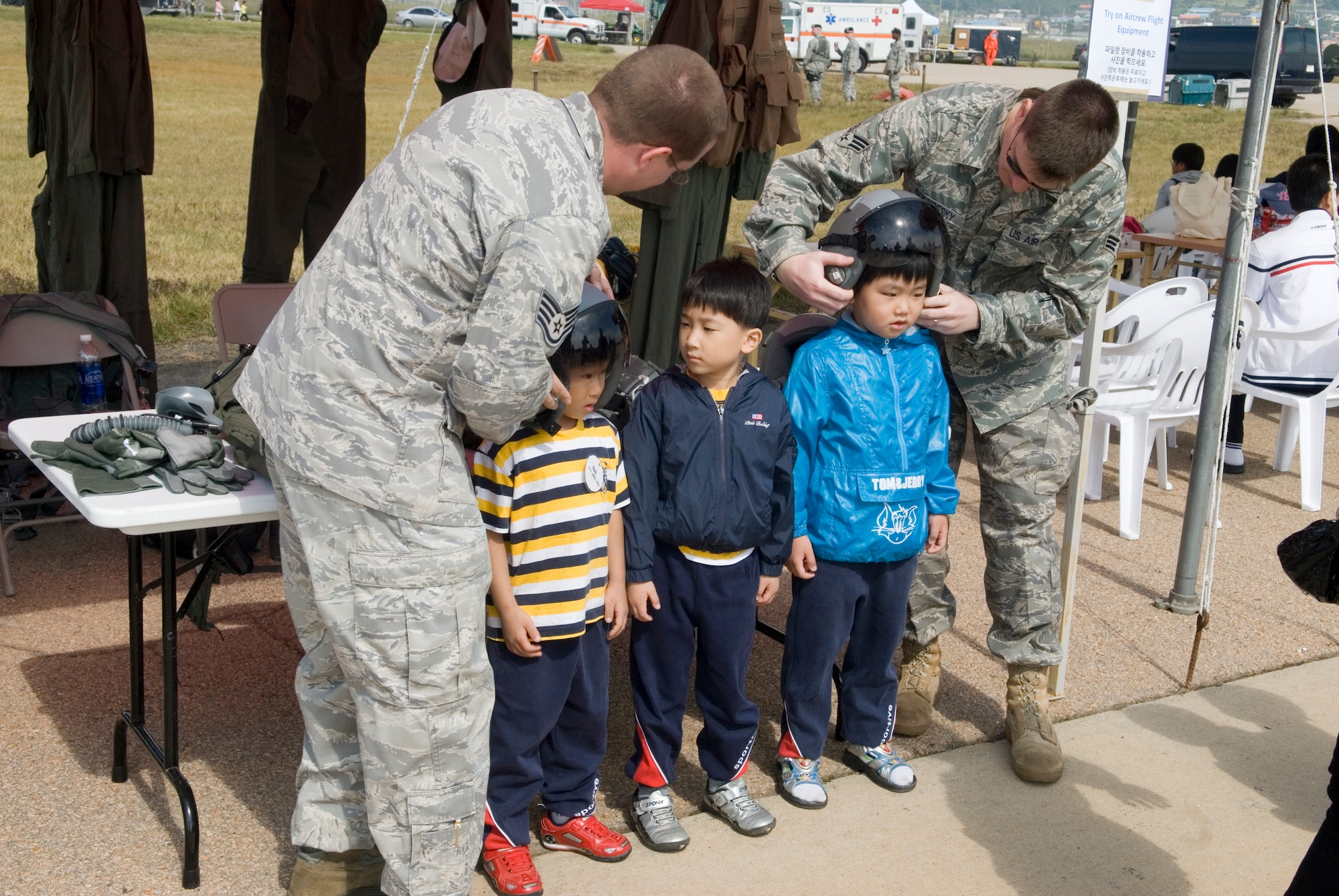 KUNSAN AIR BASE, Republic of Korea -- Staff Sgt. Robert Bradshaw and Senior Airman Evan Bonkofsky, 8th Operations Support Squadron, help Gunsan City school children try on aircrew flight equipment during the Kunsan Air Base Open House and Gunsan Appreciation Day here Oct. 1, 2010. The base opened its doors to the local community and held events including an F-16 Fighting Falcon fly-by, Korean dance performances, static displays, organizational booths, military working dog demonstrations, aircraft munitions-loading competitions, music and more. (U.S. Air Force photo/Senior Airman Ciara Wymbs)