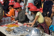 KUNSAN AIR BASE, Republic of Korea -- Gunsan City school children choose souvenirs from the 8th Civil Engineer Squadron fire department table during the Kunsan Air Base Open House and Gunsan Appreciation Day here Oct. 1, 2010. The base opened its doors to the local community and held events including an F-16 Fighting Falcon fly-by, Korean dance performances, static displays, organizational booths, military working dog demonstrations, aircraft munitions-loading competitions, music and more. (U.S. Air Force photo/Senior Airman Ciara Wymbs)
