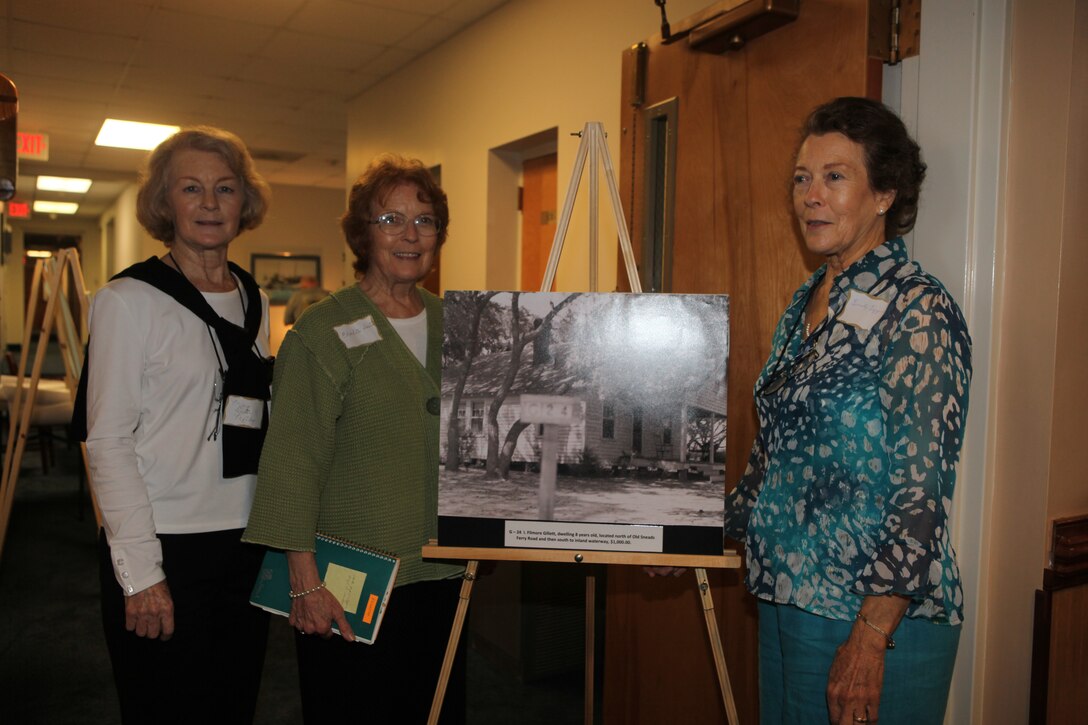 (From left to right) Mary Dexter Mobley, Charlotte Dexter and Emily Dexter Ezzell, sisters and descendants of former landowners of Marine Corps Base Camp Lejeune, pose by a photo of their original home during the landowners annual reunion at Courthouse Bay aboard the base, Oct. 3.  Original landowners and family members – some who spanned more than five generations – traveled from across the nation to attend the event.