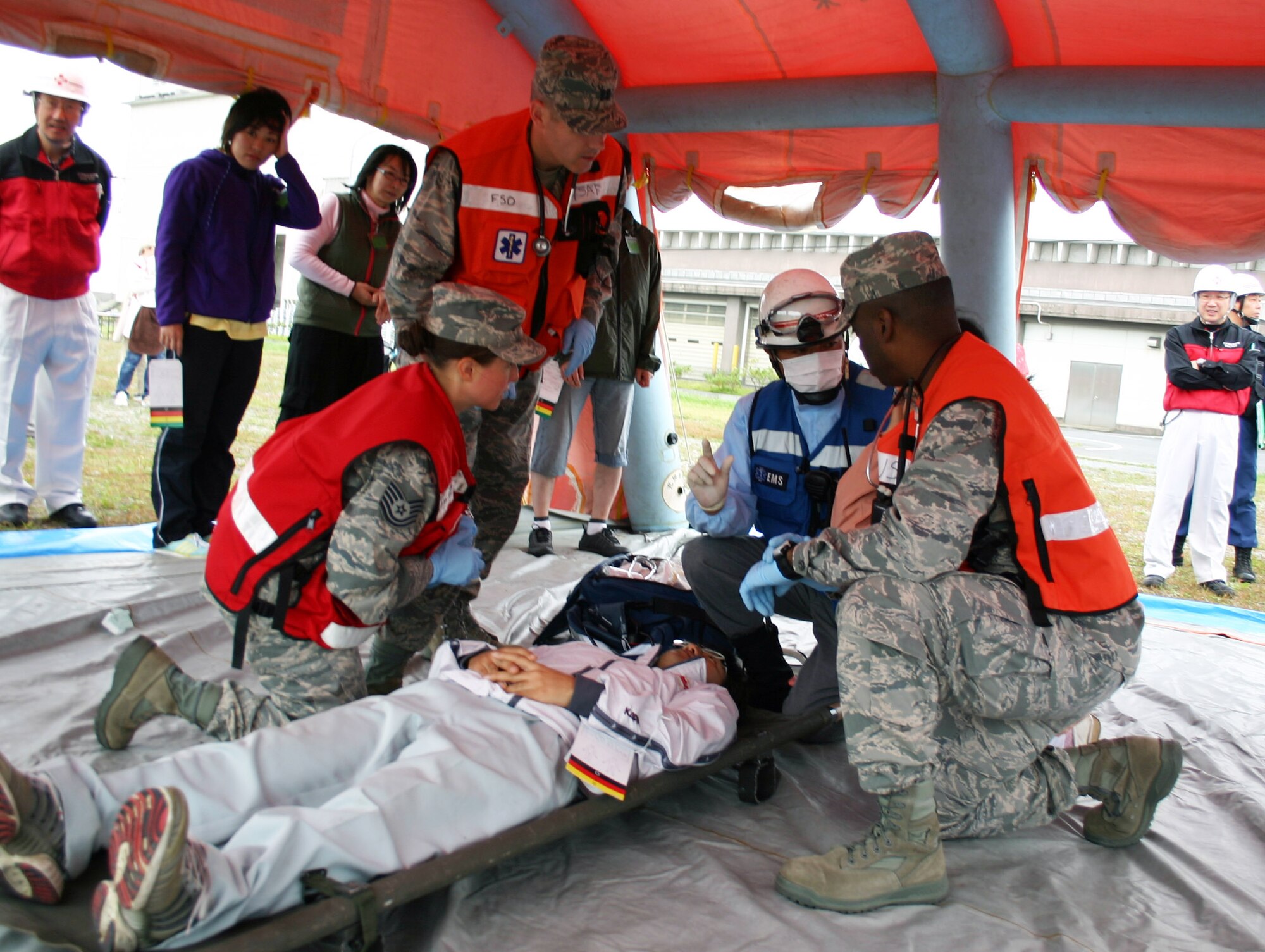 Emergency responders from the 35th Medical Operations Squadron, U.S. Air Force Capt. Michael Brough, Tech. Sgt. Sarah Ortega-Russell and Maj. Mario Maxwell, discuss a simulated earthquake victim’s injuries with a Japanese first responder at Misawa City Sea Port, Oct. 3, 2010, during the 2010 Misawa City Disaster Drill. The bilateral exercise included Misawa City and Aomori Prefecture government agencies, Japanese Ground and Air Self-Defense Forces in northern Japan, and 35th Fighter Wing personnel. (U.S. Air Force photo by Tech. Sgt. Kelly White/Released)  