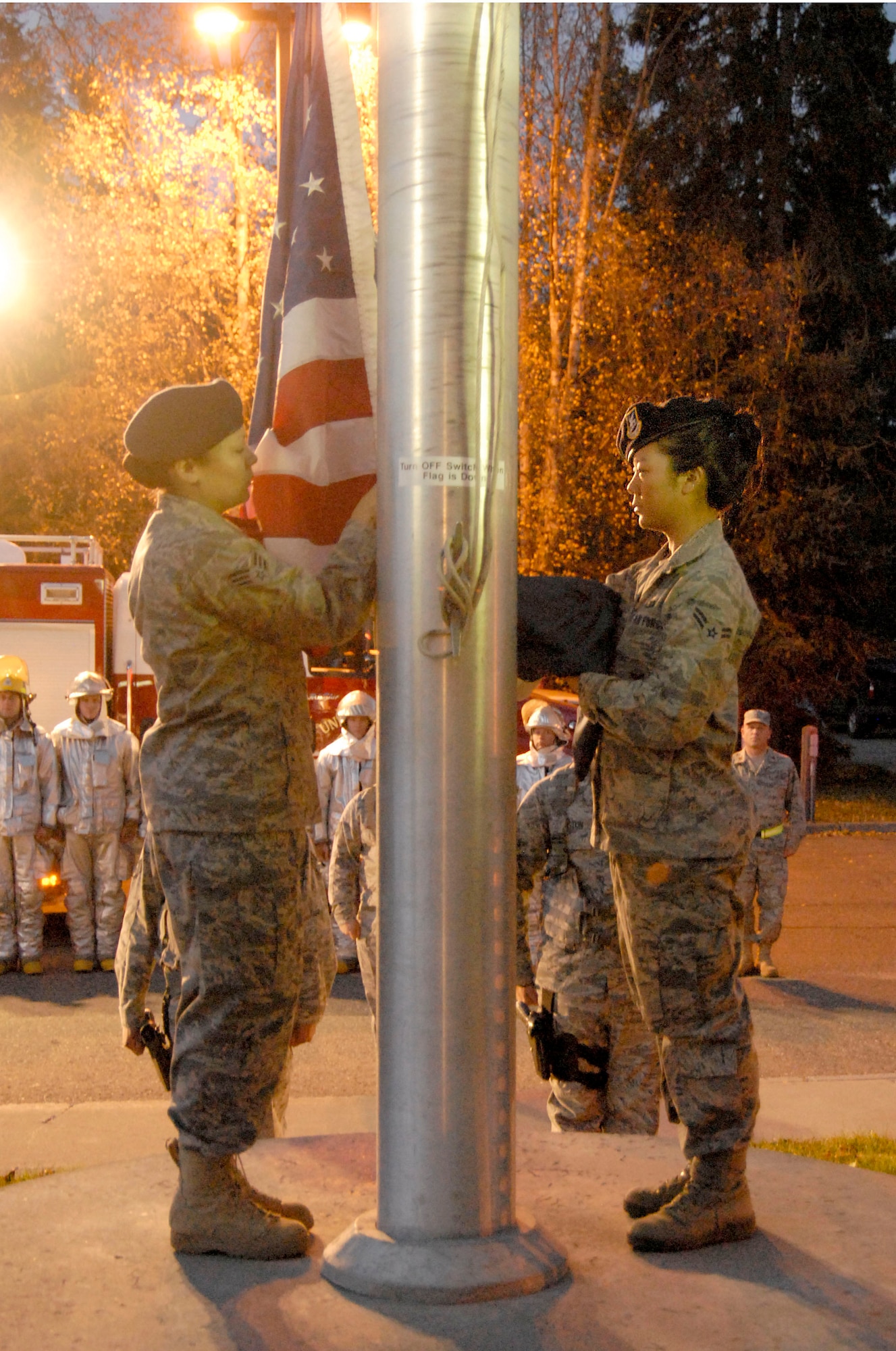 KULIS AIR NATIONAL GUARD BASE, Alaska -- Senior Airman Laurel Foster (left) and Airman 1st Class Alice Chun, both members of the 176th Security Forces Squadron, prepare to raise the U.S. flag as part of an Oct. 3, 2010 ceremony here marking National Fallen Firefighters Memorial Weekend. Fire departments around the country annually observe the ceremony, organized by the National Fallen Firefighters Foundation and the Department of Homeland Security's U.S. Fire Administration. Alaska Air National Guard photo by Master Sgt. Shannon Oleson.