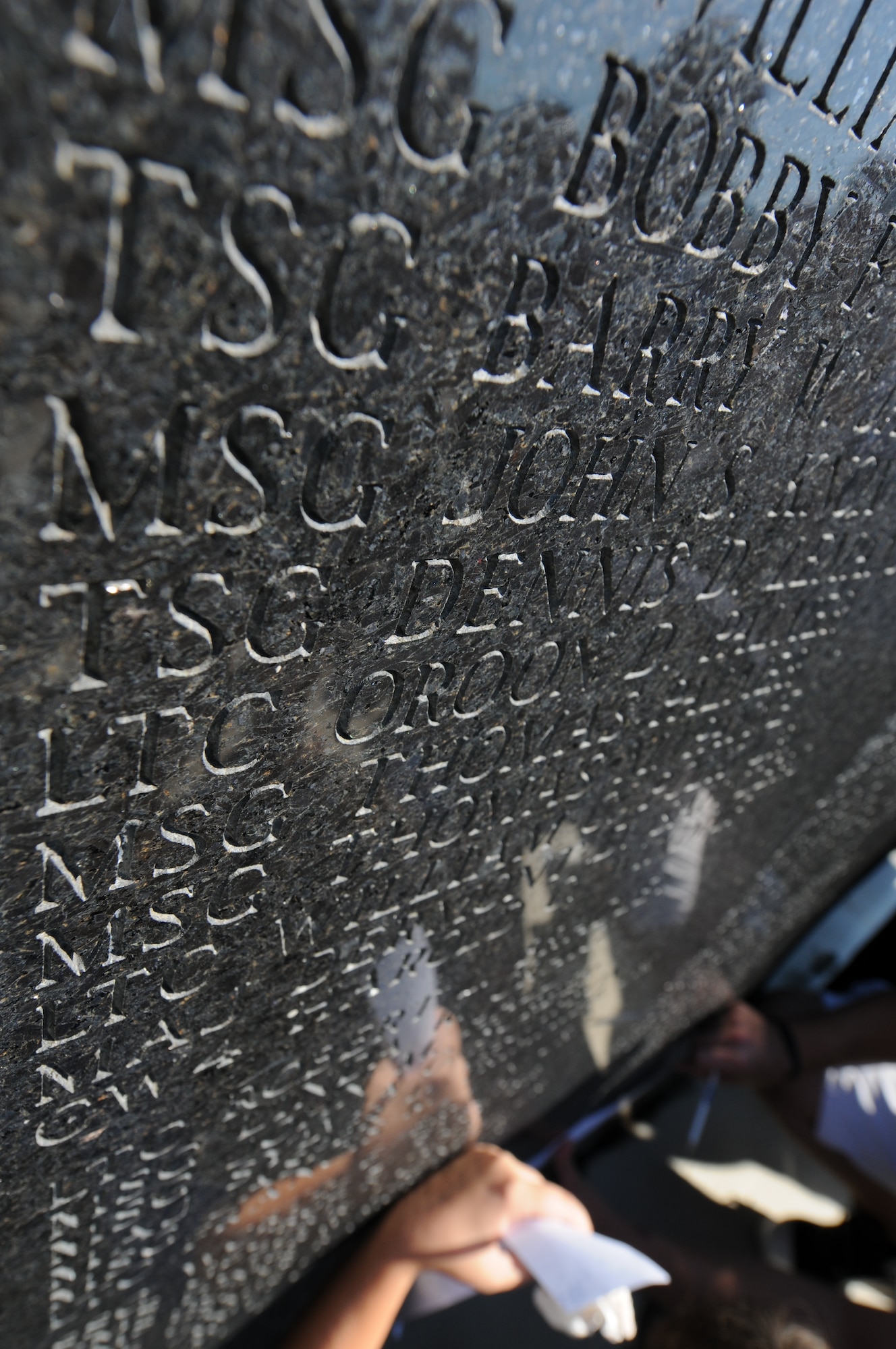 Charlotte, N.C. -- Sunlight is reflected onto names of deceased airmen of the NC Air National Guard while families etch their loved ones names onto paper during an annual memorial service at the 145th Airlift Wing. Photo by Tech. Sgt. Brian E. Christiansen, N.C. Air National Guard.