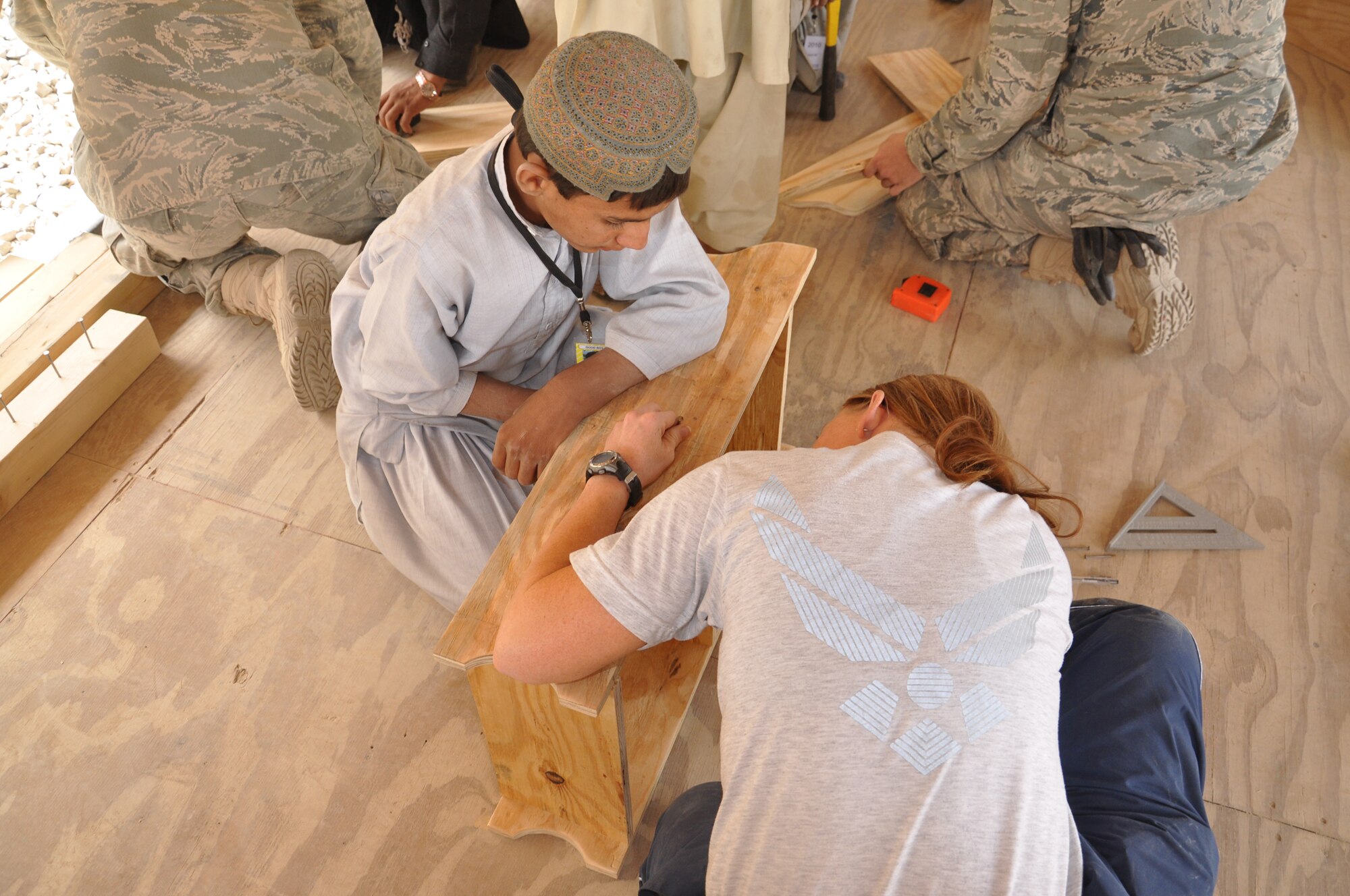 Air Force Staff Sgt. Aimi Mlekoday helps an Afghan boy build shelving for the Commander Kandahar Air Field-sponsored Bazaar School. Mlekoday, from Norman, Okla., is a Reserve operations management helper supporting military operations in the region while assigned to the 777th Expeditionary Prime BEEF Squadron. (U.S. Army photo)