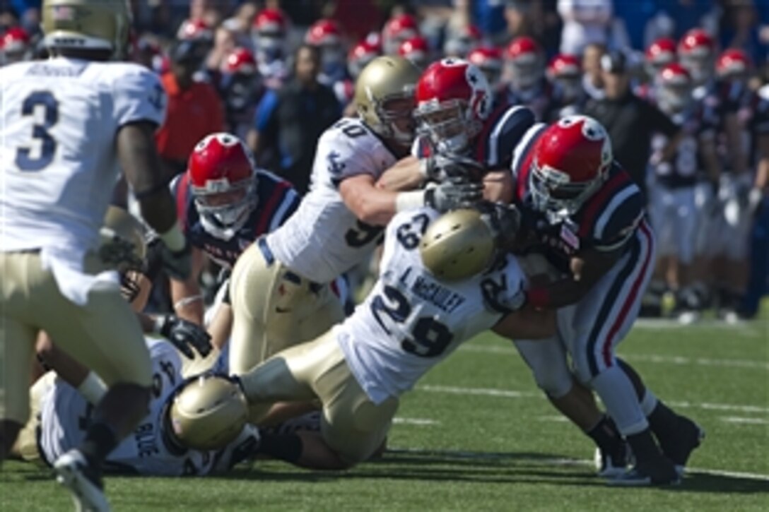 U.S. Naval Academy Midshipman Linebacker Aaron McCauley and Defensive End Billy Yarborough tackle U.S. Air Force Academy Falcon Running Back Jared Tew in Colorado Springs, Colo., Oct. 2, 2010. The Falcons ended a seven-year drought defeating the Midshipmen 14-6. 