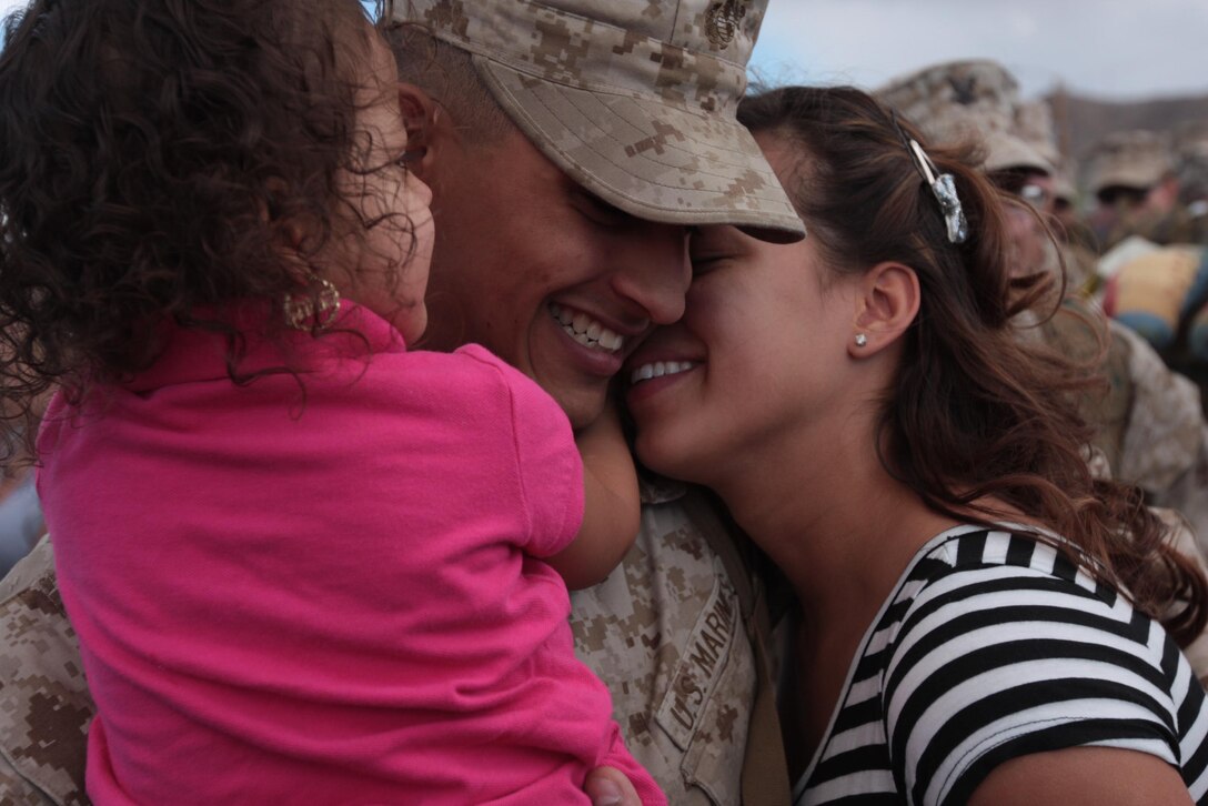 Corporal Carmelo Sierra, a field radio operator with Regimental Combat Team 7, hugs his wife, Obdulia, and daughter, Juliana, during the homecoming of RCT-7’s main body Monday at Del Valle Field Oct. 4, 2010.