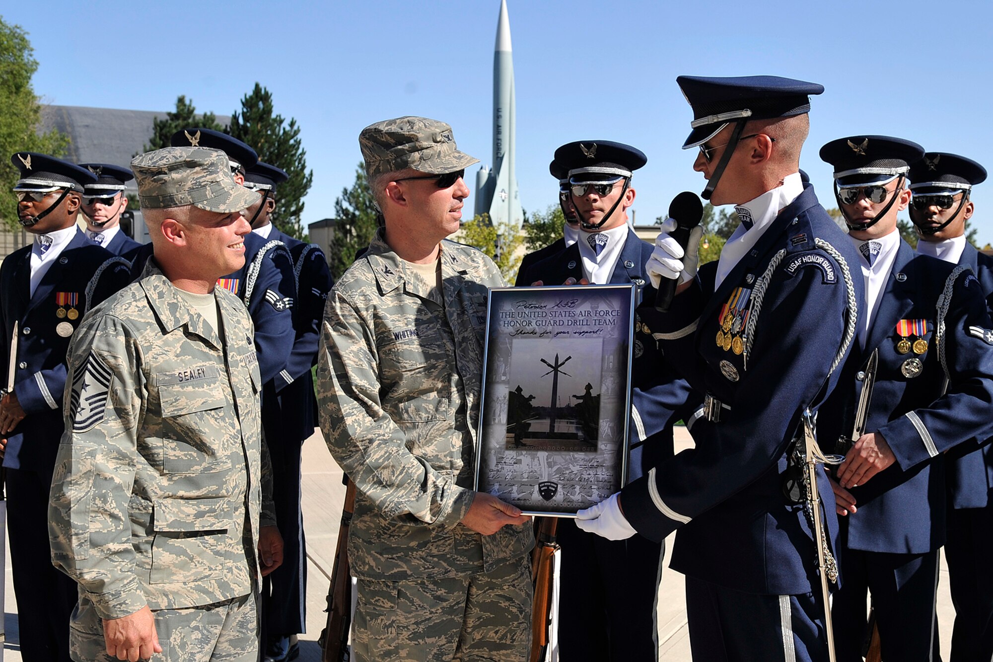 PETERSON AIR FORCE BASE, Colo. – Col. Stephen N. Whiting, 21st Space Wing commander, and Chief Master Sgt. Robert Sealey, 21st SW command chief, accept from Capt. Chad Frey, Air Force Honor Guard Drill Team flight commander, a framed photo signed by all the members of the Air Force Honor Guard Drill Team after their performance Sept. 29 at Peterson Air Force Base Museum's Medal of Honor Park. The drill team performed a variety of tightly choreographed maneuvers including spinning, flipping, and tossing 11-pound rifles with fixed bayonets. (U.S. Air Force photo/Rob L. Bussard)