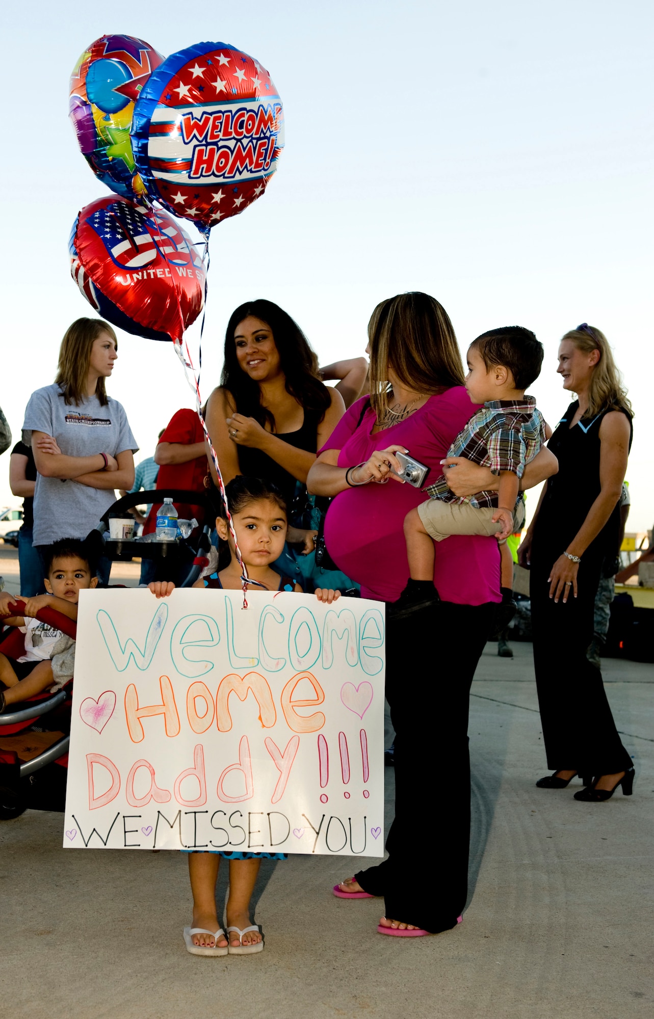 HOLLOMAN AIR FORCE BASE, N.M. -- Aelizae Vigil, daughter of Senior Airman Larry Vigil III, 49th Maintenance Squadron, waits for her father while holding a welcome back greeting sign Oct. 1, 2010, just before he returned from a deployment. The deployment sent 285 'Fightin' 49ers' and 12 F-22A Raptors to the island of Okinawa, Japan, where clear airspace overhead and miles of water around allowed the fifth generation fighters to train alongside Kadena Air Base's F-15C Eagles and KC-135 Stratotankers, while also working with Marine Corps F/A-18 Hornets. (U.S. Air Force photo by Tech. Sgt. Alan Port / Released)