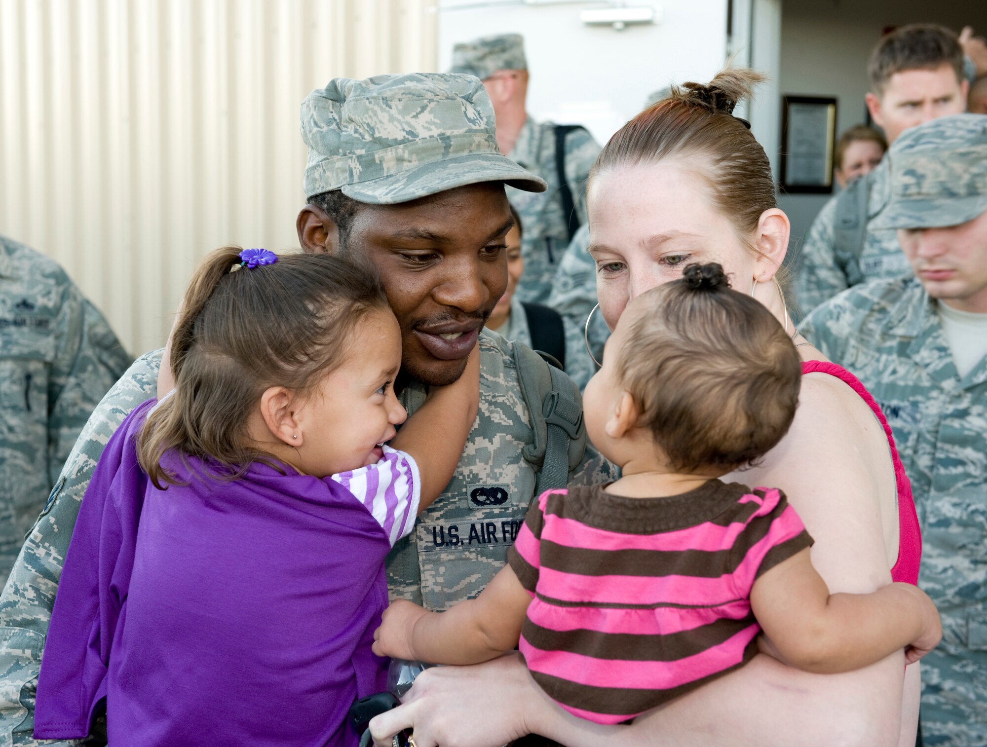 HOLLOMAN AIR FORCE BASE, N.M. -- Senior Airman Micheal Thompson, 49th Aircraft Maintenance Squadron, reunites with his family after returning from a deployment Oct. 1, 2010. The deployment sent 285 'Fightin' 49ers' and 12 F-22A Raptors to the island of Okinawa, Japan, where clear airspace overhead and miles of water around allowed the fifth generation fighters to train alongside Kadena Air Base's F-15C Eagles and KC-135 Stratotankers, while also working with Marine Corps F/A-18 Hornets. (U.S. Air Force photo by Tech. Sgt. Alan Port / Released)