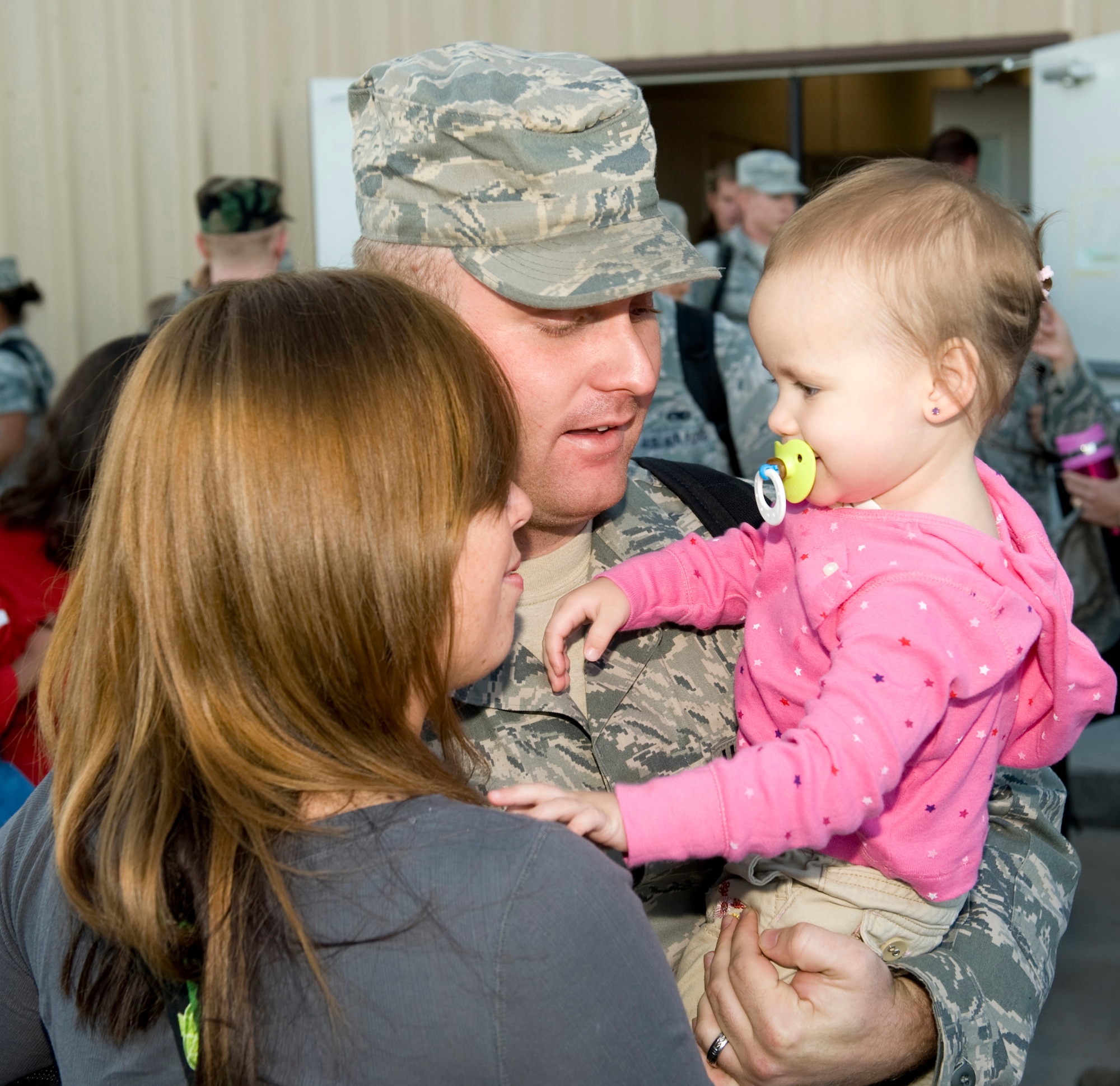 HOLLOMAN AIR FORCE BASE, N.M. -- Staff Sgt. Alexander Kelly, 49th Maintenance Squadron, reunites with his family after returning from a deployment Oct. 1, 2010. The deployment sent 285 'Fightin' 49ers' and 12 F-22A Raptors to the island of Okinawa, Japan, where clear airspace overhead and miles of water around allowed the fifth generation fighters to train alongside Kadena Air Base's F-15C Eagles and KC-135 Stratotankers, while also working with Marine Corps F/A-18 Hornets.  (U.S. Air Force photo by Tech. Sgt. Alan Port / Released)