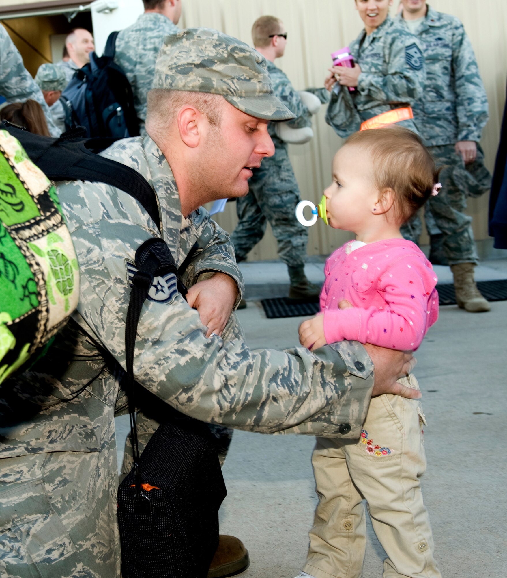 HOLLOMAN AIR FORCE BASE, N.M. -- Staff Sgt. Alexander Kelly, 49th Maintenance Squadron, reunites with his daughter after returning from a deployment Oct. 1, 2010. The deployment sent 285 'Fightin' 49ers' and 12 F-22A Raptors to the island of Okinawa, Japan, where clear airspace overhead and miles of water around allowed the fifth generation fighters to train alongside Kadena Air Base's F-15C Eagles and KC-135 Stratotankers, while also working with Marine Corps F/A-18 Hornets. (U.S. Air Force photo by Tech. Sgt. Alan Port / Released)