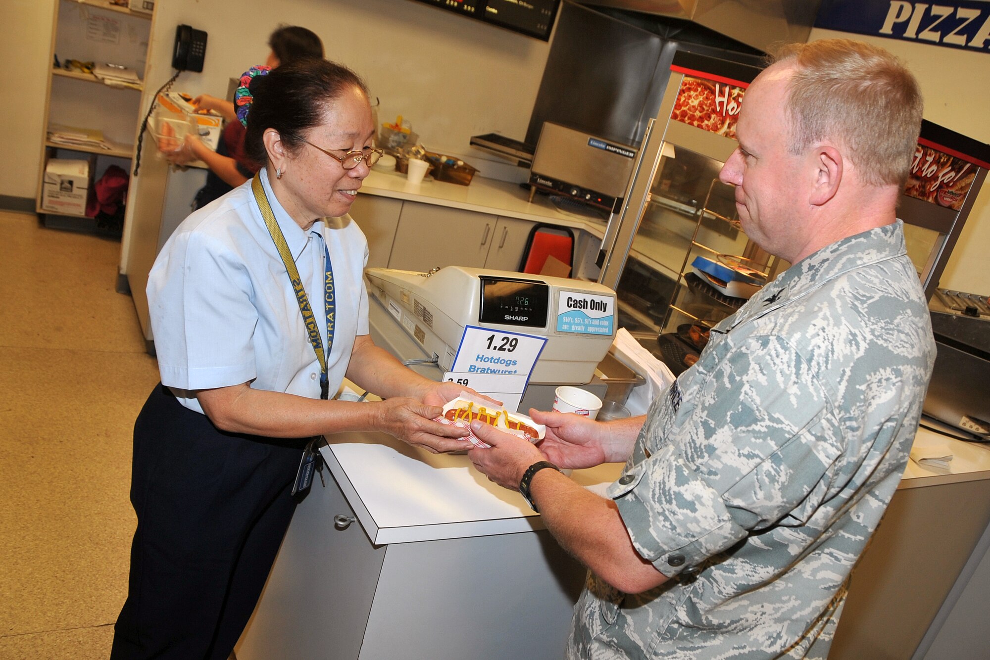 OFFUTT AIR FORCE BASE, Neb. - Col. Michael Allshouse, 55th Mission Support Group commander, buys one last hot dog from Gloria Love, Army and Air Force Exchange Service food service manager at D's Dog Stand in the Martin Bomber Building Sept. 30. After 69 years of service, the hot dog stand closed its doors, leaving behind a legacy of satisfied customers and life-long relationships. U.S. Air Force photo by Jeff Gates