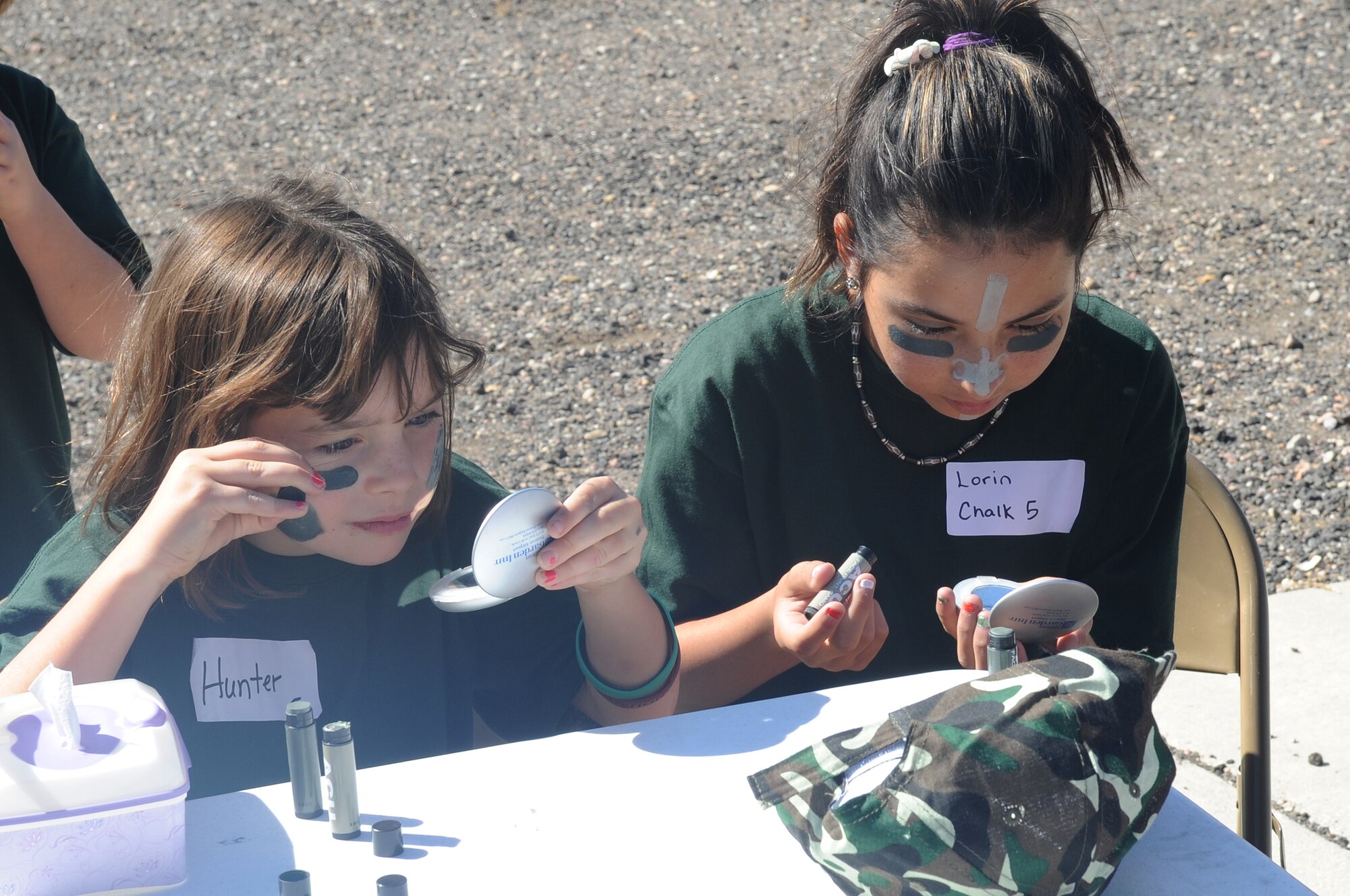 BUCKLEY AIR FORCE BASE, Colo.-- Nine-year-old Hunter Duncan and Lorin Ringler, 11, cover their faces with camouflage paint at the Family Mock Deployment Oct. 2 at Camp Rattlesnake. The children received little backpacks with the camouflage paint inside, which they got to keep. (U.S. Air Force Photo by Airman Manisha Vasquez) 