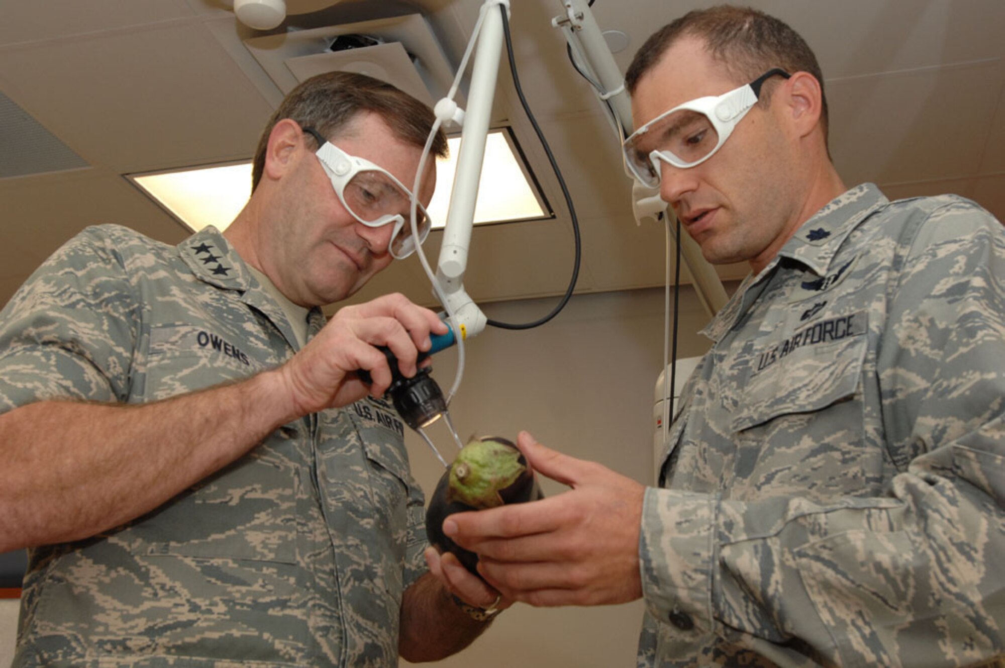 Lt. Col. (Dr.) Chad Hivnor, 59th Medical Wing associate director of dermatology (right), shows Lt. Gen. Douglas Owens, the new vice commander for Air Education and Training Command (left), how a carbon dioxide fractional laser works using an egg plant in Wilford Hall Medical Center's dermatology department, Lackland Air Force Base, Texas, Oct. 1, 2010.  Dr. Hivnor treats battle scars on wounded warrior burn victims using a fractional laser. (U.S. Air Force photo by Staff Sgt. Robert Barnett)
