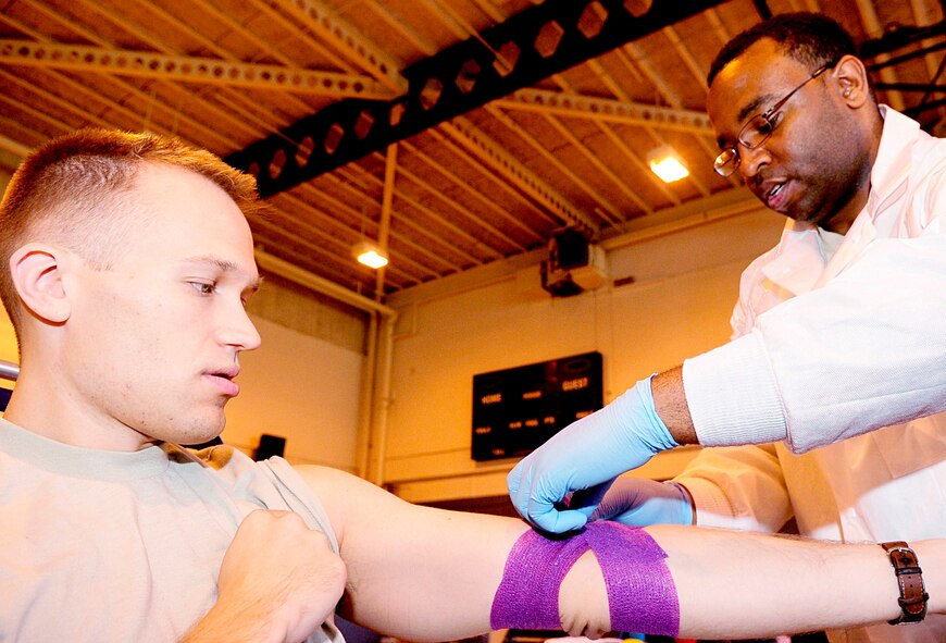 RAF MILDENHALL, England -- Capt. Jeffery Martin, 100th Air Refueling Wing, has his arm bandaged by SPC. Reginald Scott, Armed Services Blood Program medical lab technician, after donating blood at the blood drive here Sept. 30. The bandage is applied to each donor after giving blood to stop the bleeding and to prevent infection. (U.S. Air Force photo/Senior Airman Ethan Morgan) 