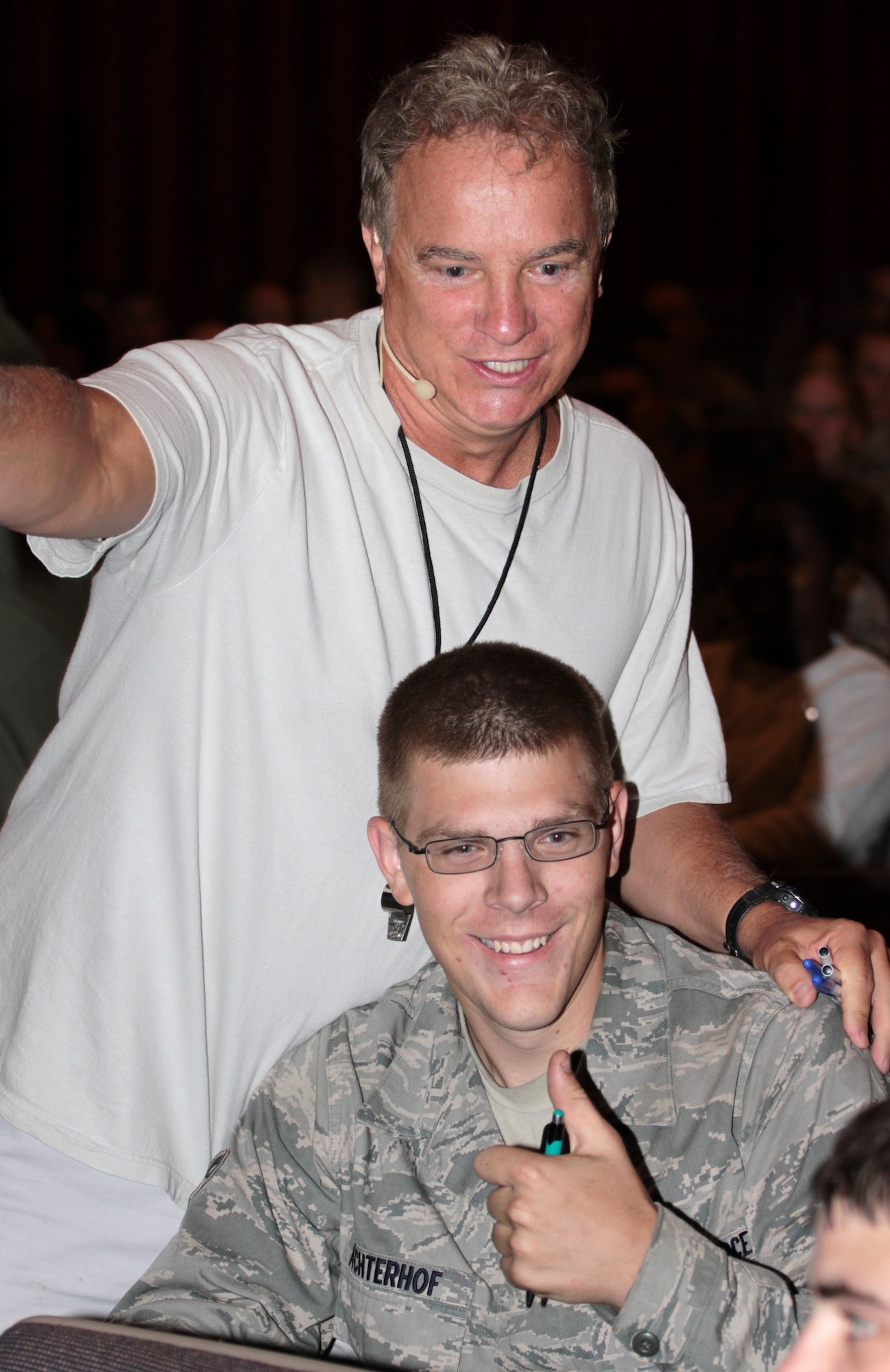 Steve Verret, an Improv Comedy Club Traffic School traffic safety comedian, hands out a pen and paper to Airman 1st Class Michael Achterhof, 19th Logistics Readiness Squadron, during a safety briefing Sept. 30 at the base theater. Mr. Verret offers a fresh way to deliver traffic safety information by using comedic relief to keep the audience entertained. (U.S. Army photo by Spc. Jared Sollars)
