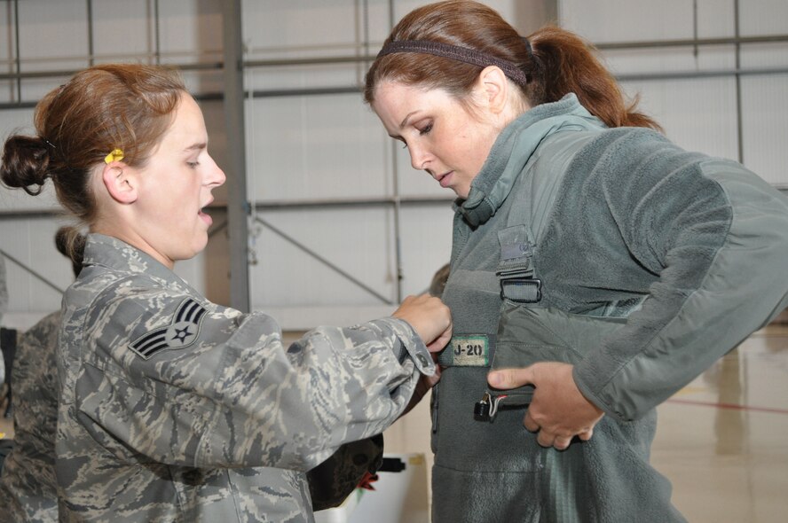 Senior Airman Destynie Duppler, assigned to the 352nd Special Operations Support Squadron, properly attaches a life preserver to Jocelyn Lombard, wife of Tech. Sgt. Mitchell Lombard assigned to the 352nd Special Operations Group, in preparation for an orientation flight over parts of England during recent Spouses Day activities.  Over 100 family members attended the annual event aimed at showing appreciation for the sacrifices spouses make to ensure successful accomplishment of the 352nd SOG and Joint Special Operations Air Command – Europe’s critical mission.  (U.S. Air Force photo/Tech. Sgt. Marelise Wood)